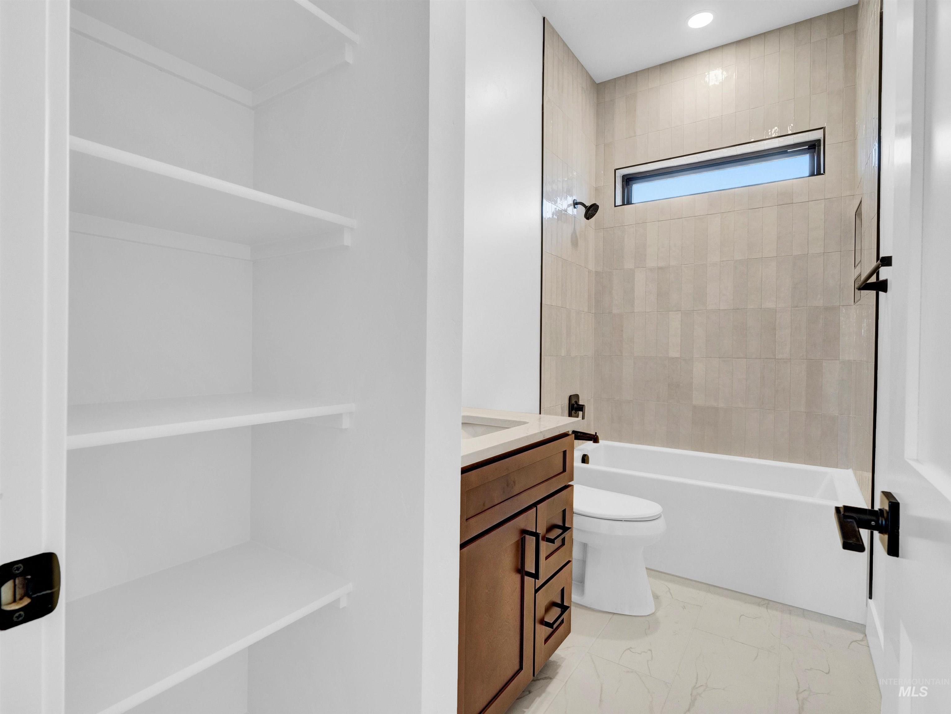 Bathroom with vanity, shower / washtub combination, marble finish flooring, and recessed lighting