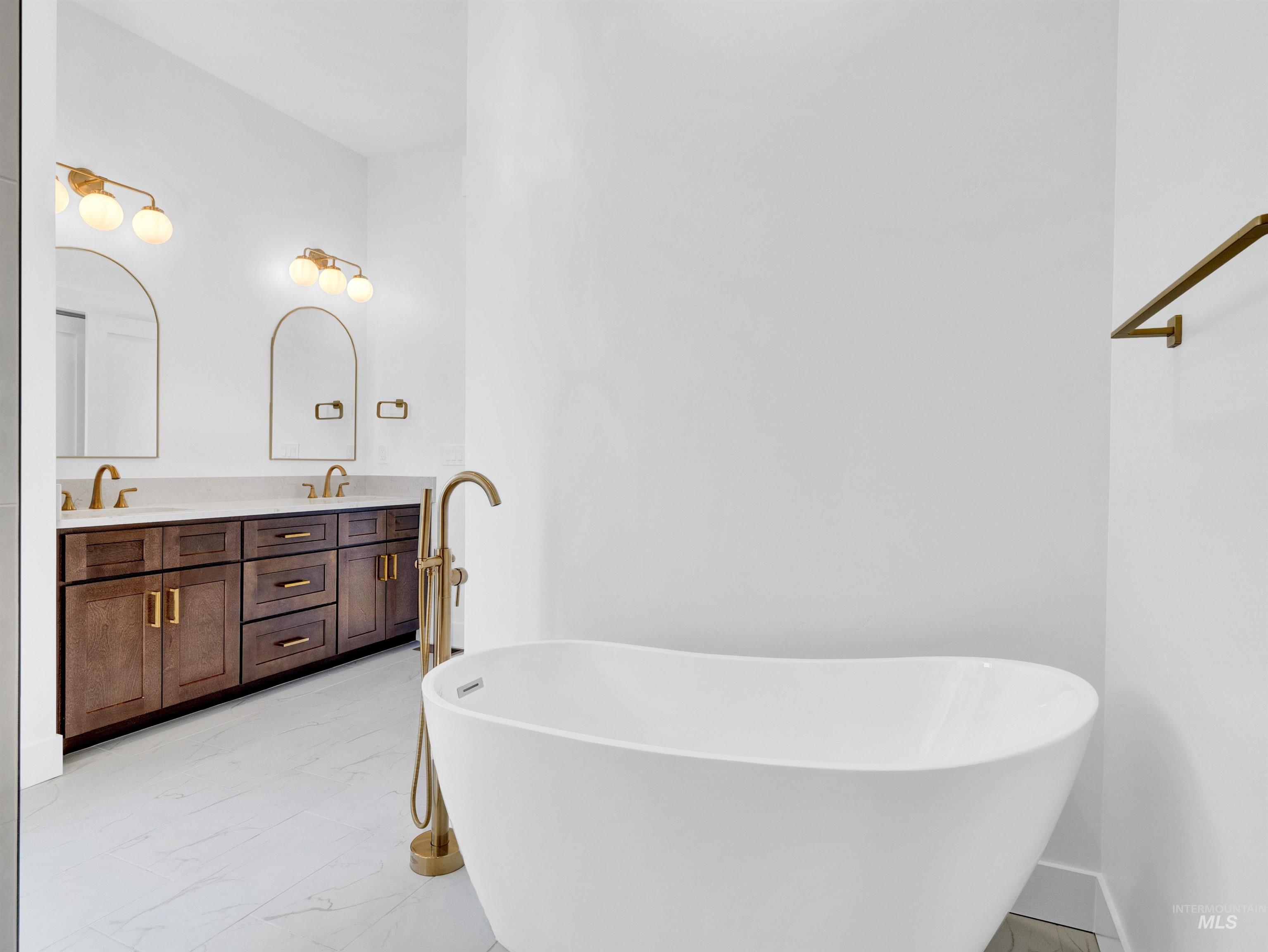 Full bath with marble finish floors, a soaking tub, and double vanity