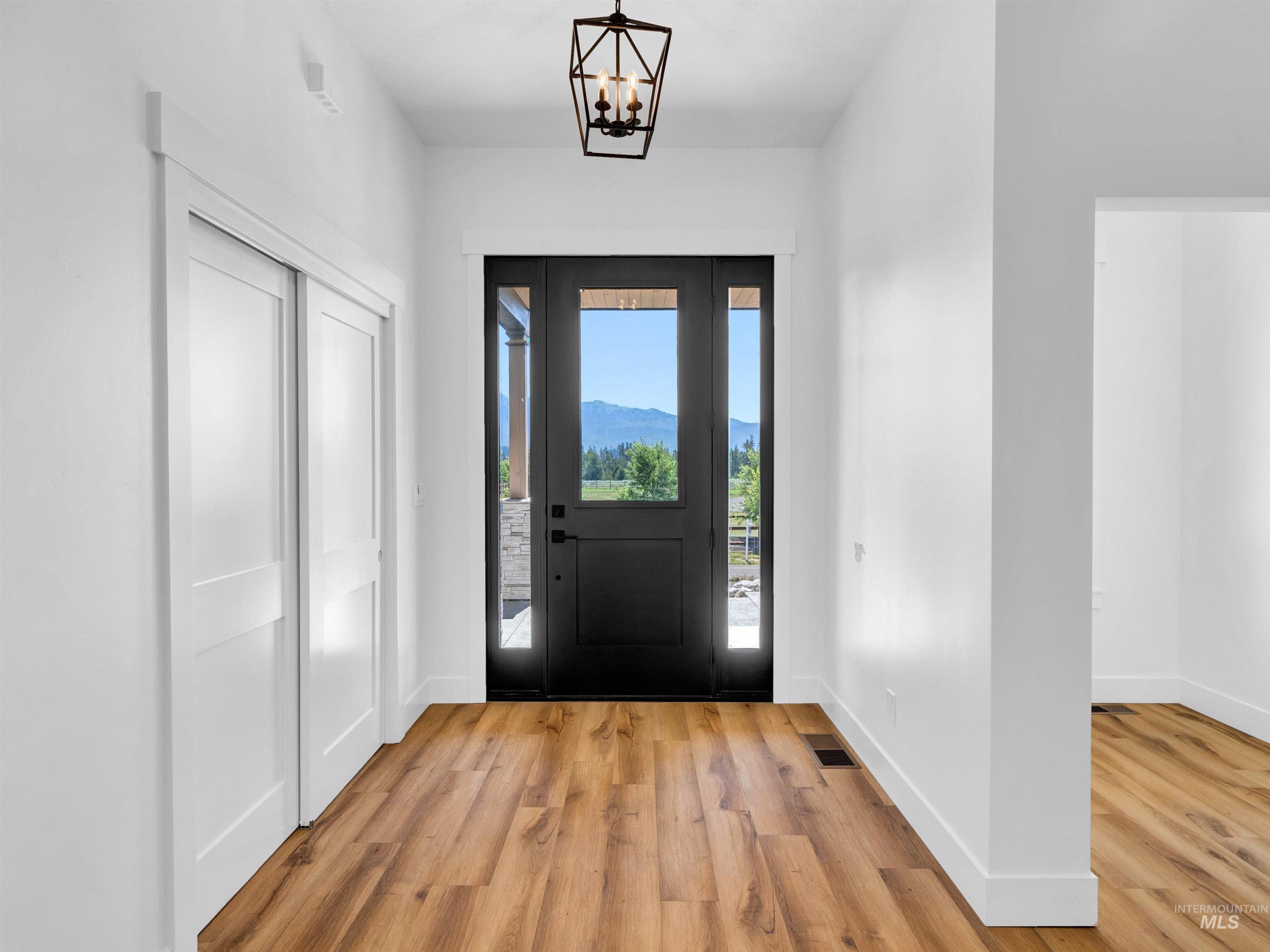 Entrance foyer with light wood finished floors, a chandelier, and a mountain view