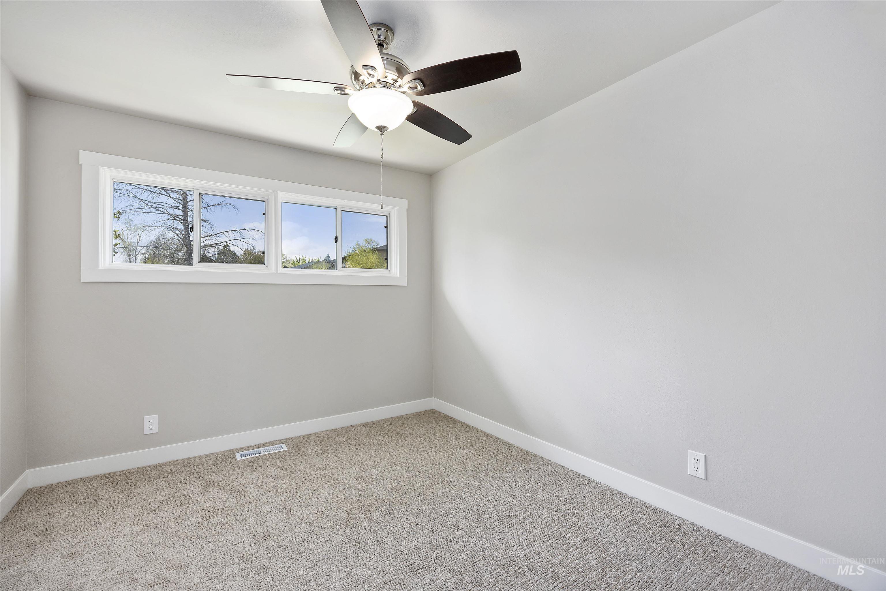 Spare room with light colored carpet and a ceiling fan