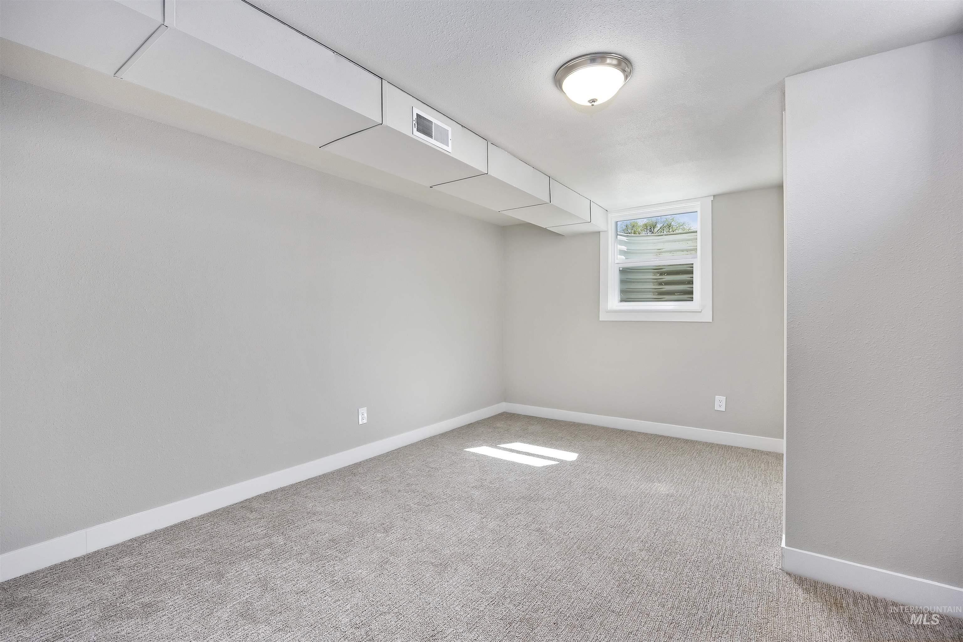 Unfurnished room featuring baseboards and light carpet