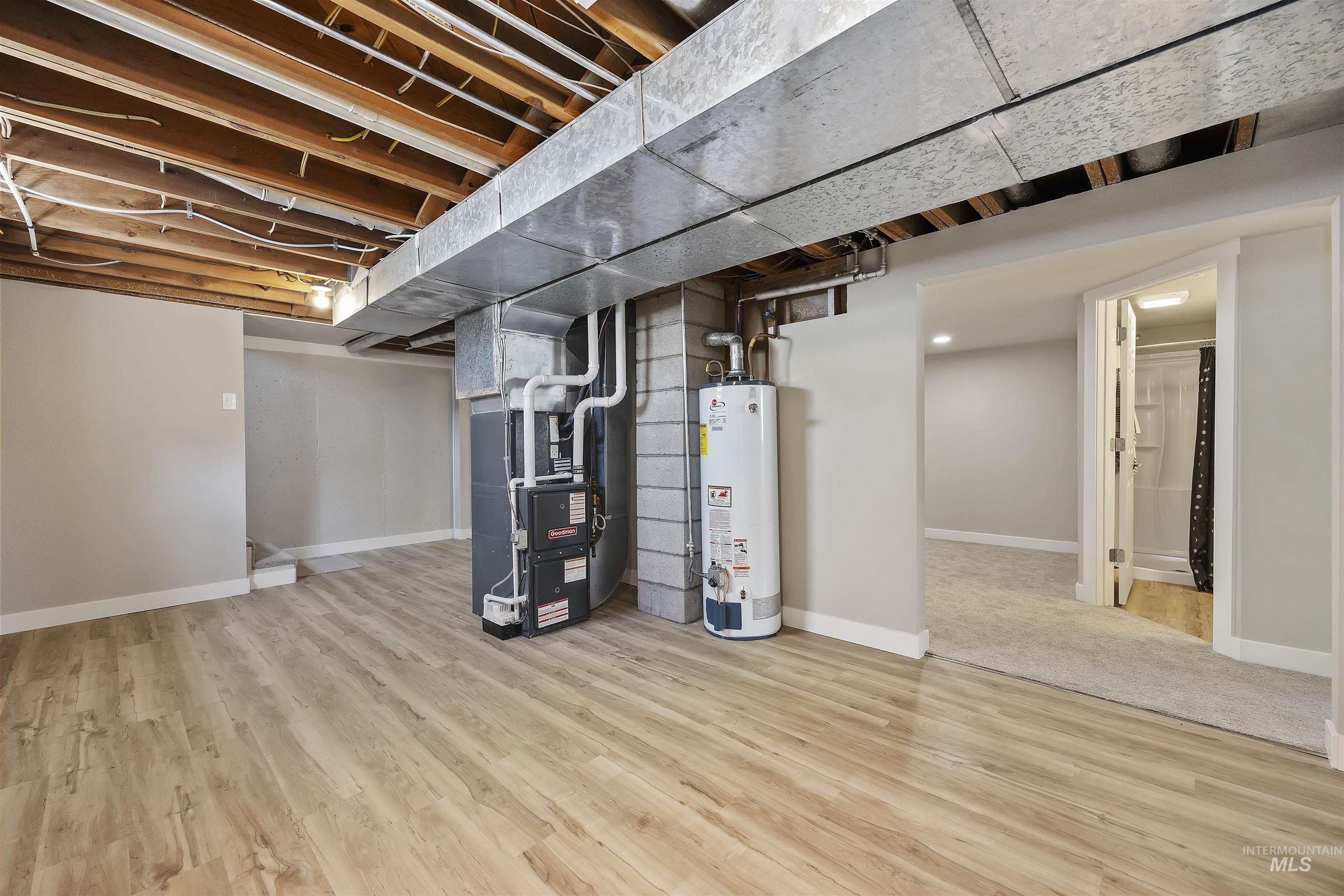 Below grade area featuring light wood-type flooring, gas water heater, and heating unit
