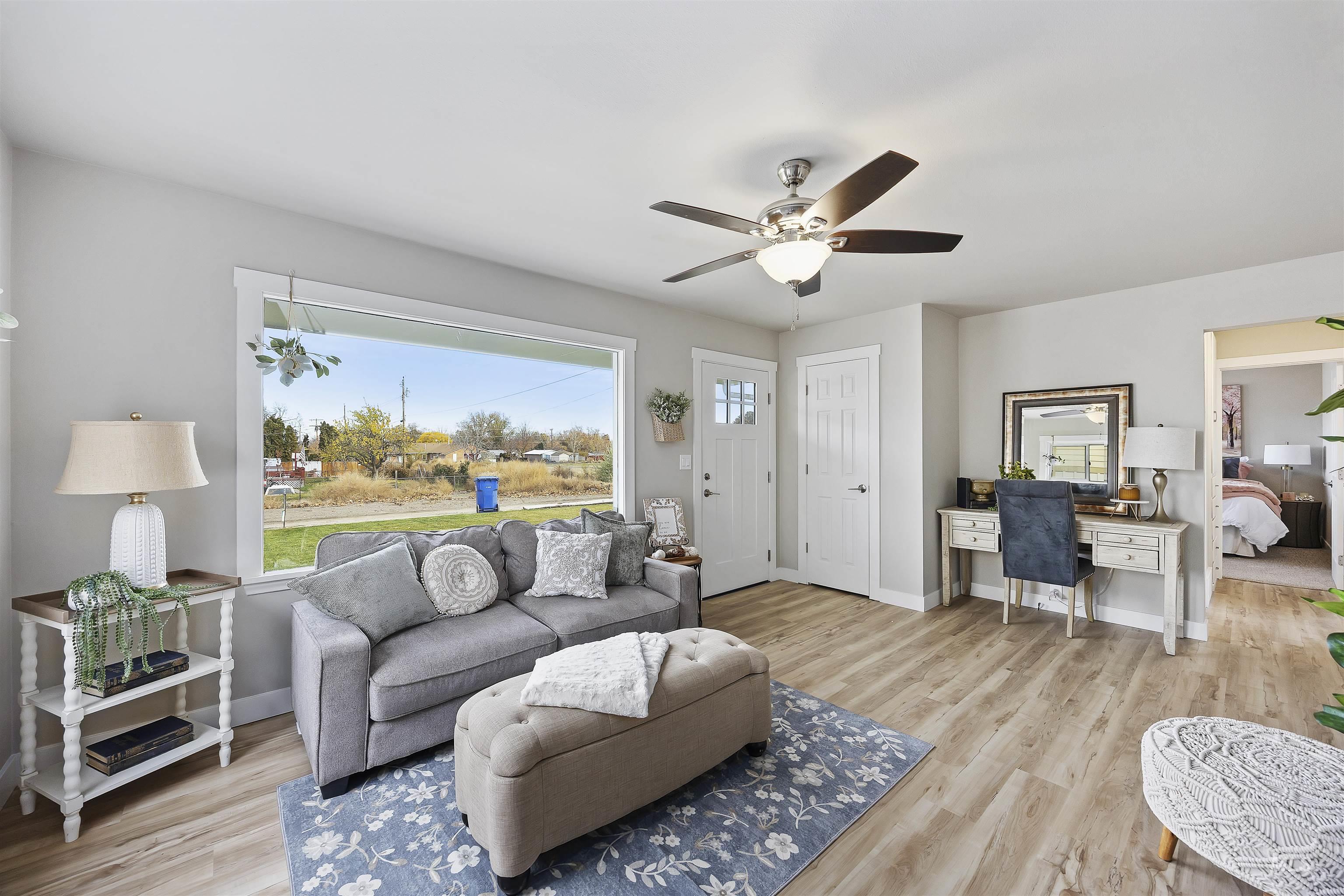 Living area with light wood finished floors, a desk, and a ceiling fan
