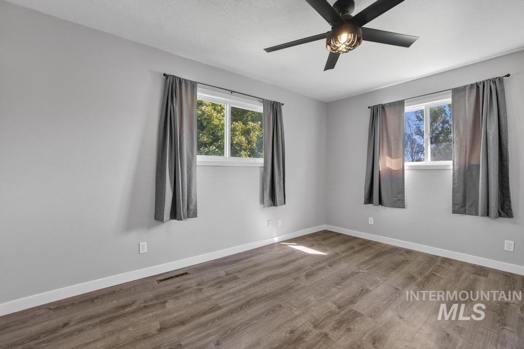 Unfurnished room featuring plenty of natural light, wood finished floors, and a ceiling fan
