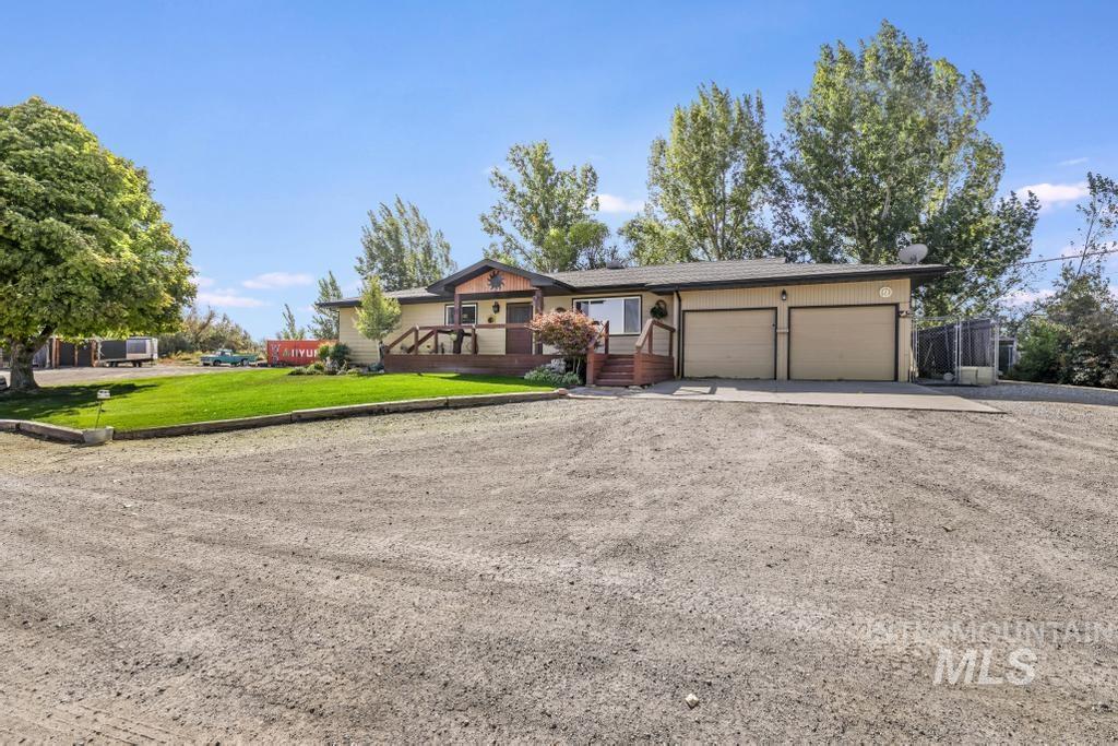 Ranch-style house featuring driveway, a front lawn, a garage, and a wooden deck