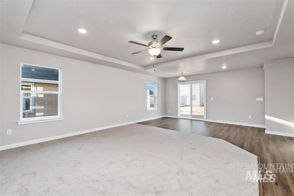 Unfurnished room featuring a raised ceiling, a ceiling fan, a smoke detector, dark wood-style floors, and recessed lighting