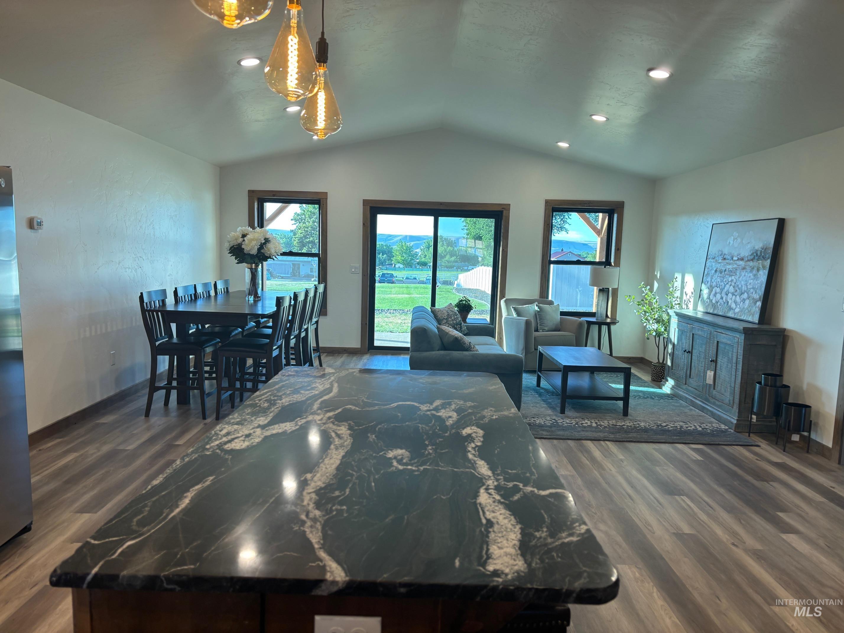 Living room with wood finished floors, plenty of natural light, lofted ceiling, and recessed lighting
