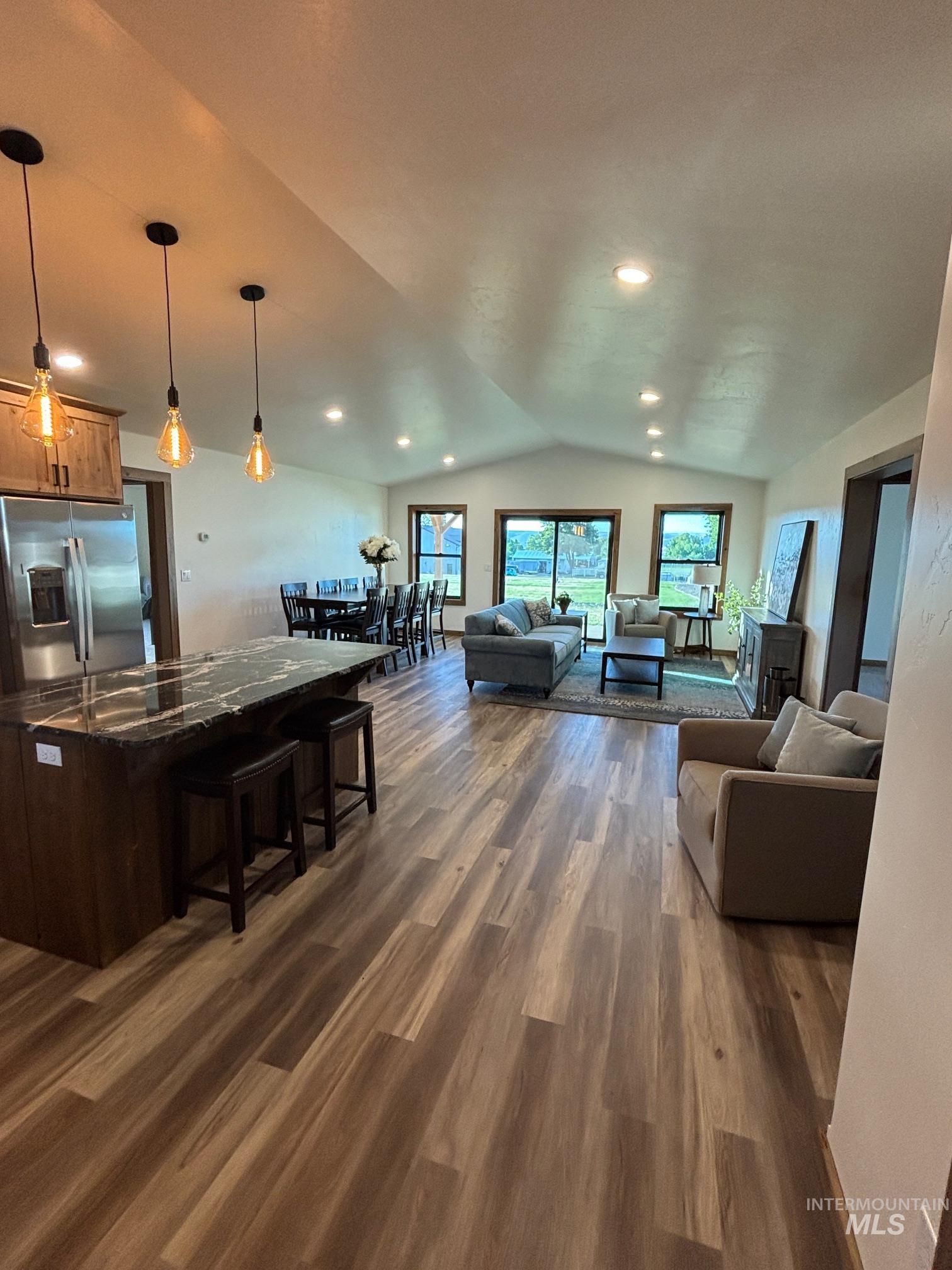 Living area featuring vaulted ceiling, dark wood-type flooring, plenty of natural light, and recessed lighting