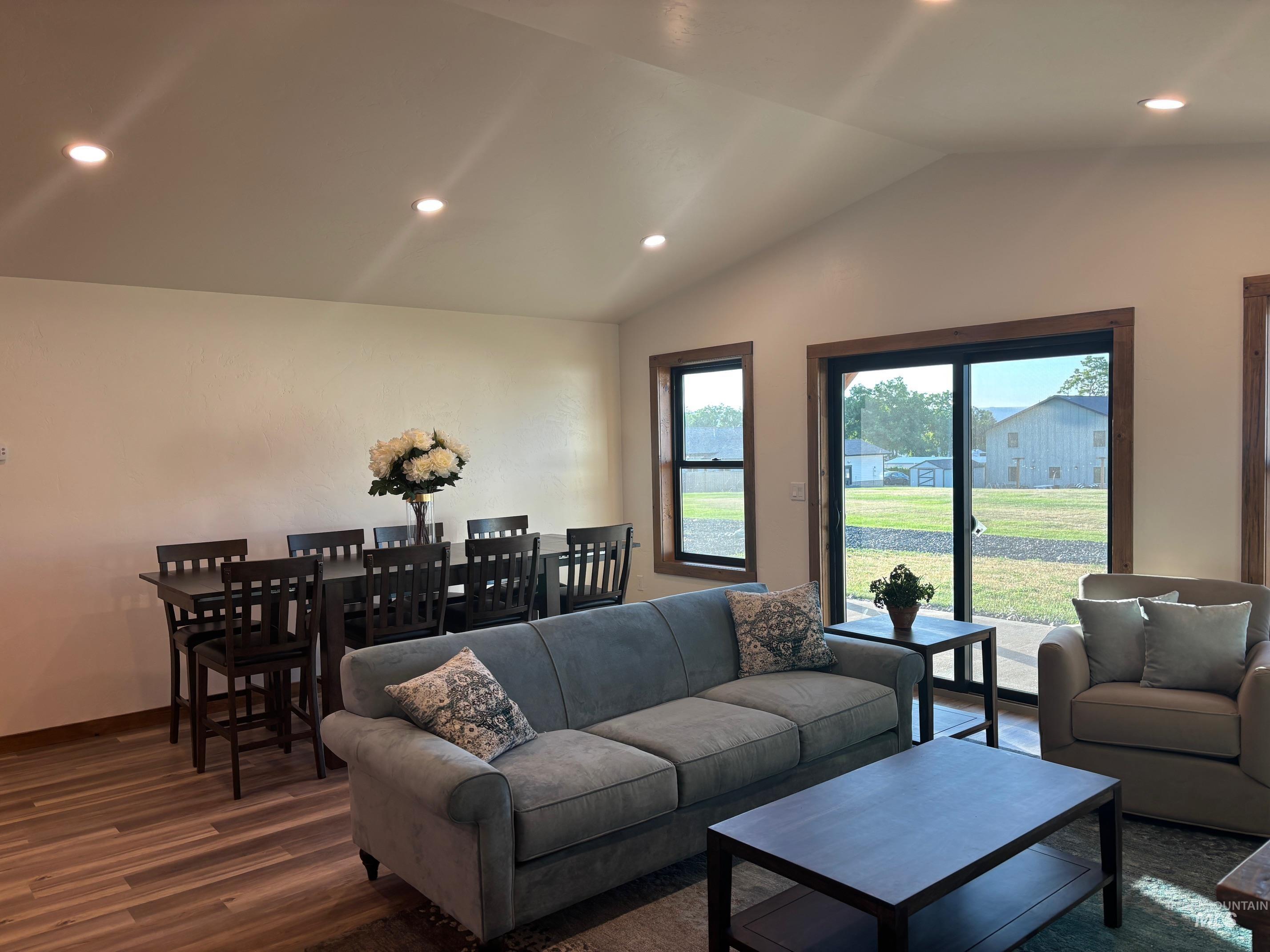 Living room with wood finished floors, lofted ceiling, and recessed lighting