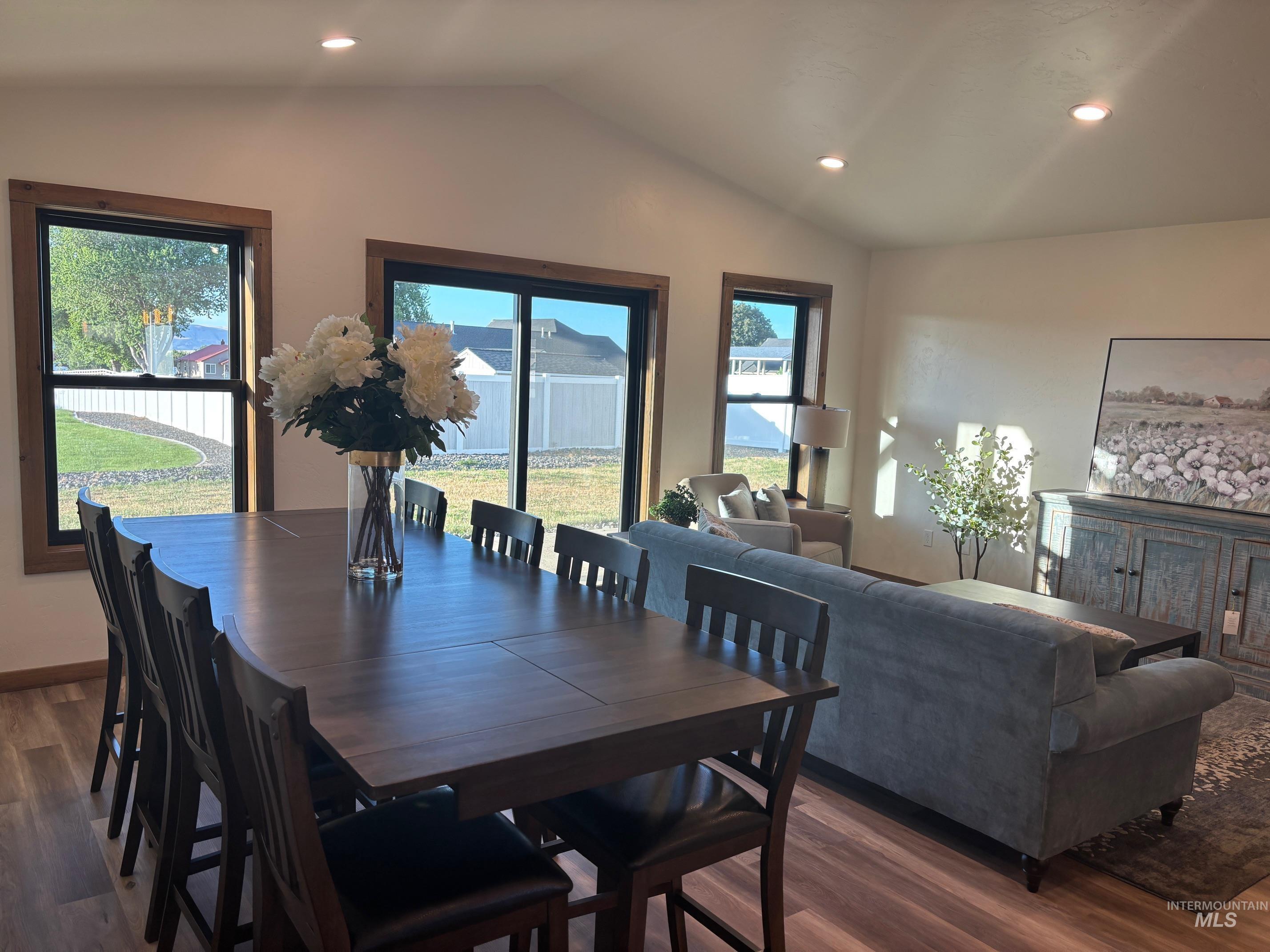 Dining room featuring dark wood finished floors, lofted ceiling, healthy amount of natural light, and recessed lighting