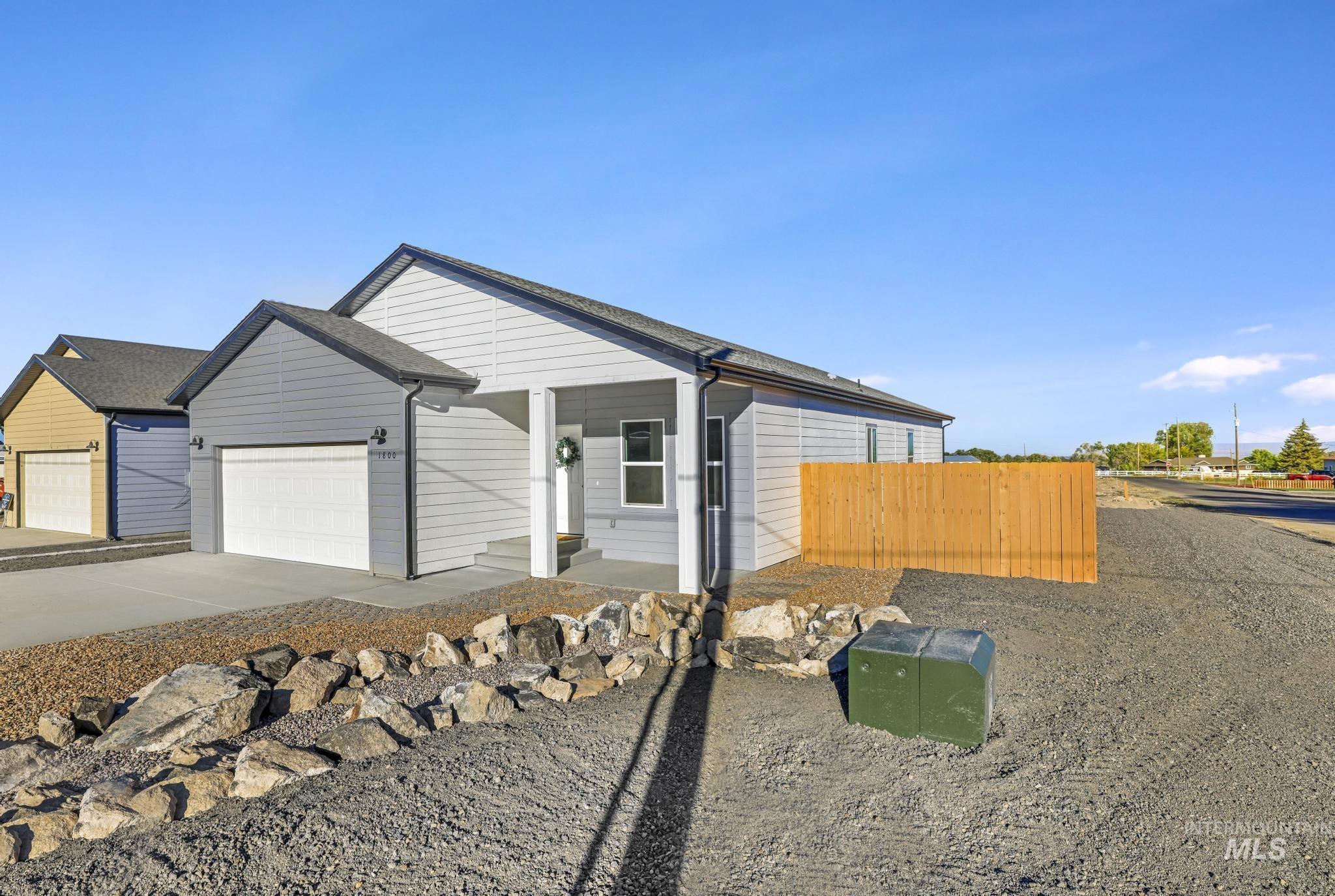 View of front of property featuring driveway, an attached garage, and covered porch