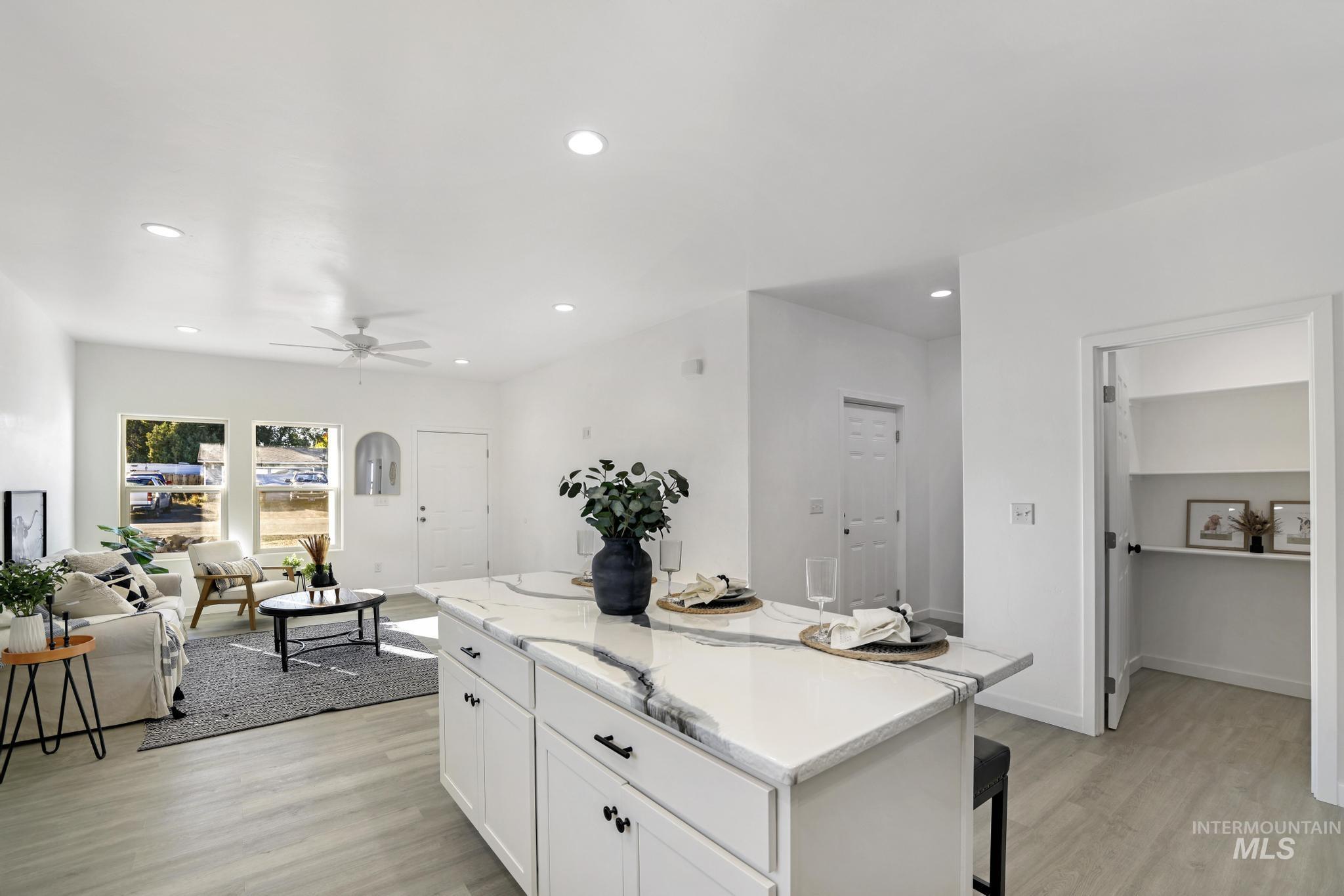 Kitchen with white cabinets, light wood-style floors, a kitchen island, recessed lighting, and a kitchen breakfast bar