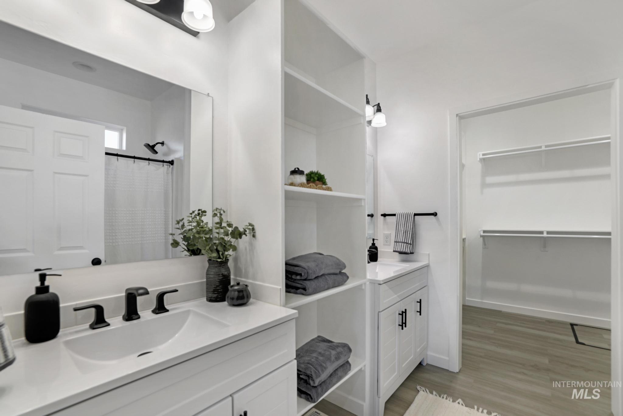 Bathroom with vanity, light wood finished floors, a walk in closet, and a shower with shower curtain