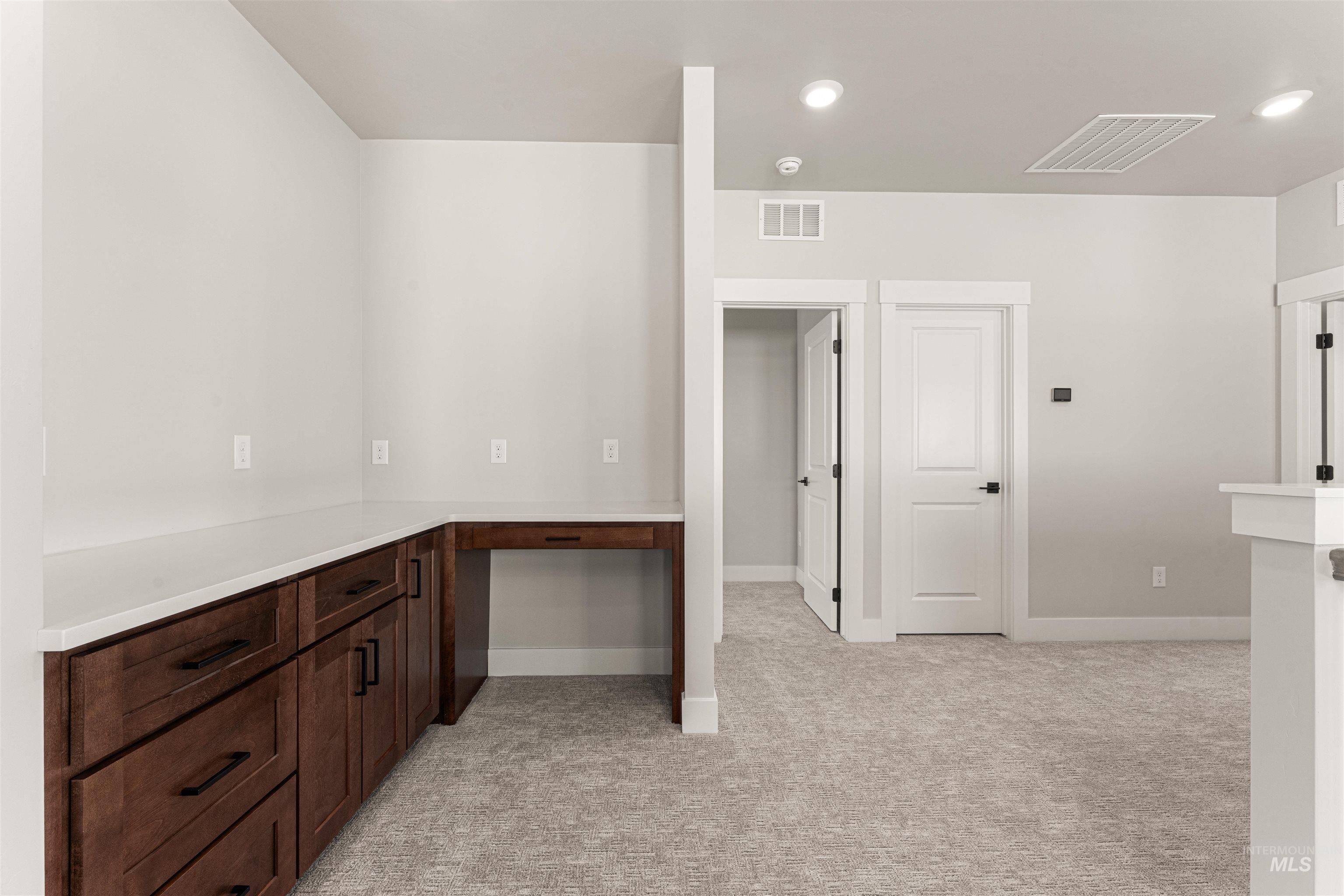 Bar with light carpet, built in desk, and recessed lighting