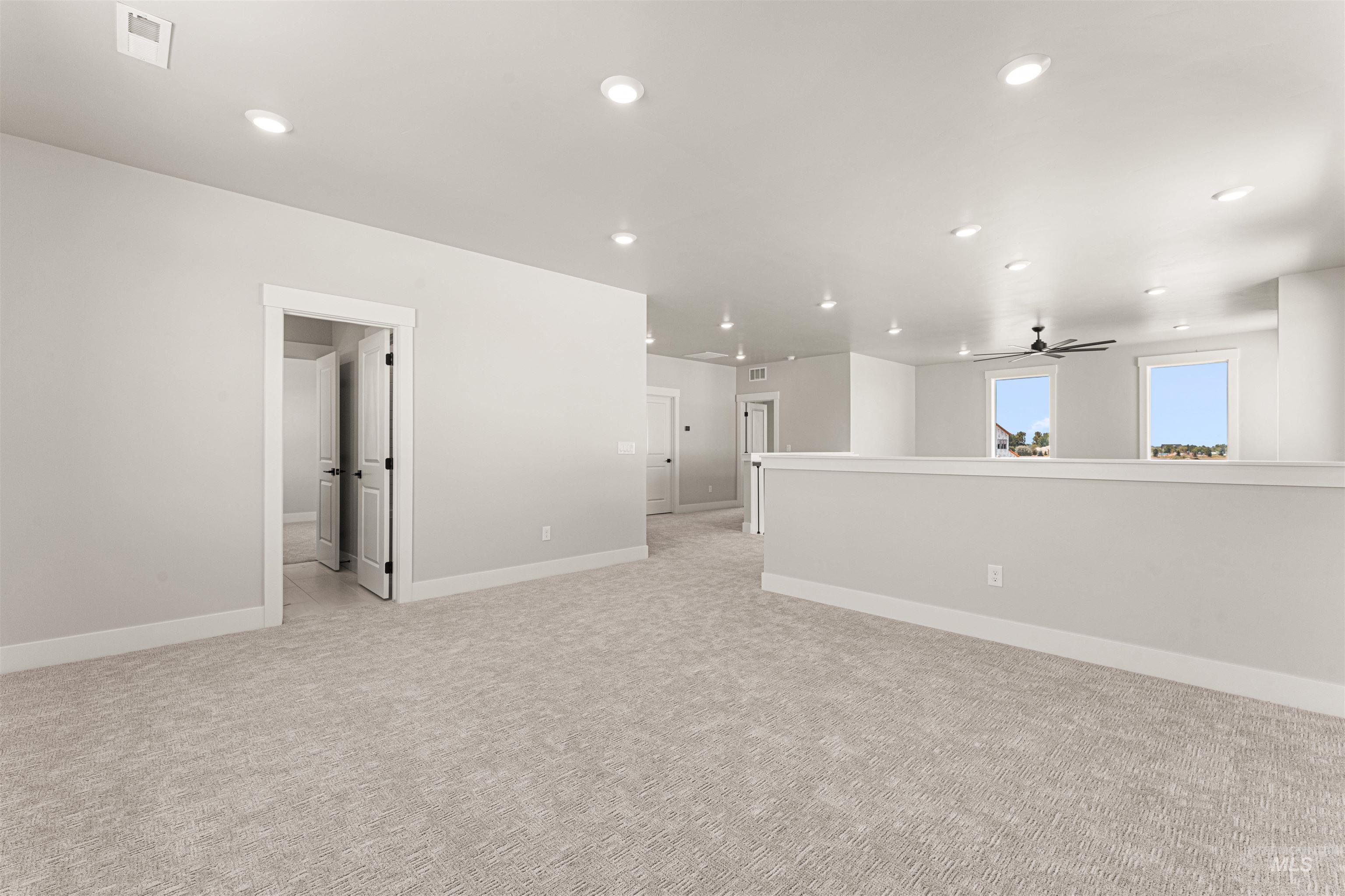 Spare room featuring light colored carpet, ceiling fan, and recessed lighting