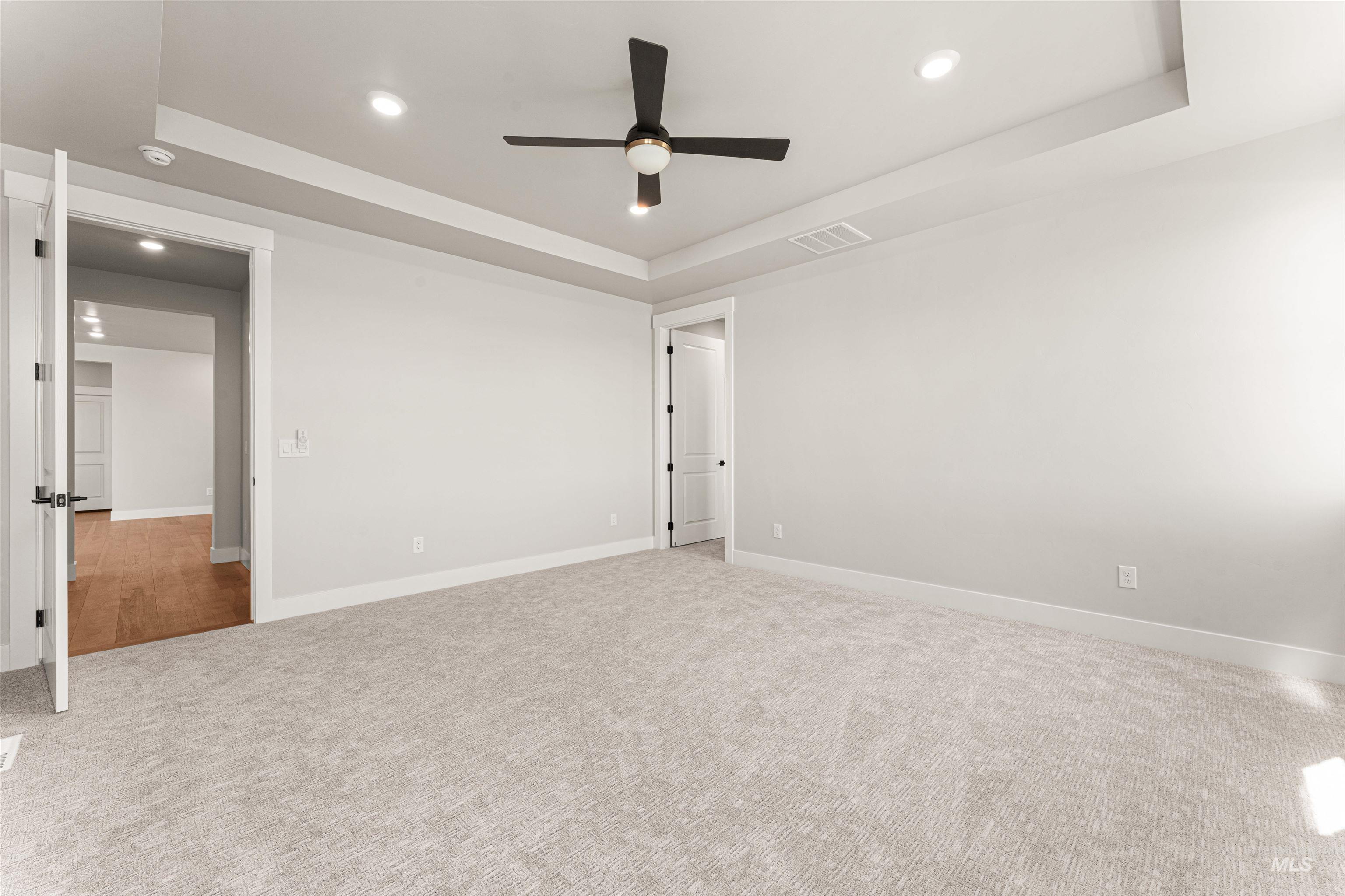 Unfurnished bedroom featuring recessed lighting, a raised ceiling, carpet floors, and ceiling fan