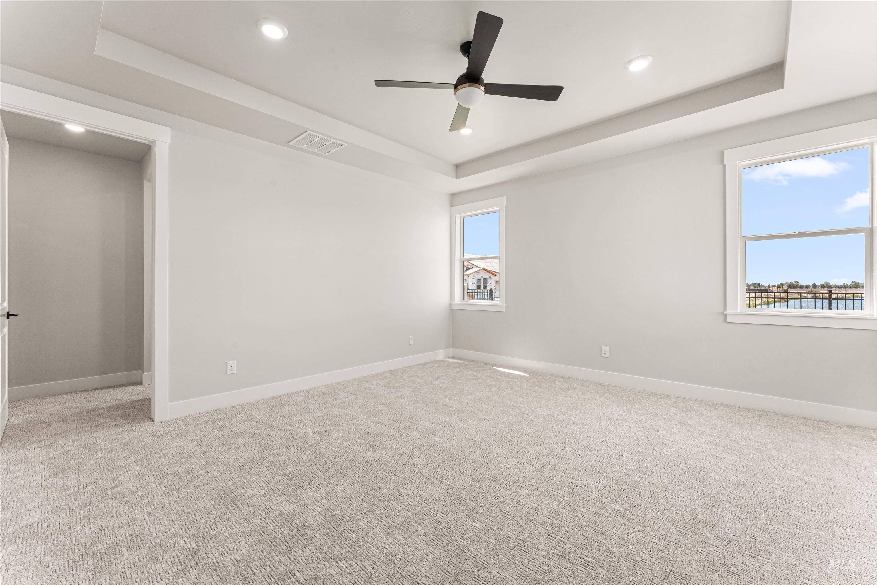 Spare room with a tray ceiling, light colored carpet, recessed lighting, and ceiling fan