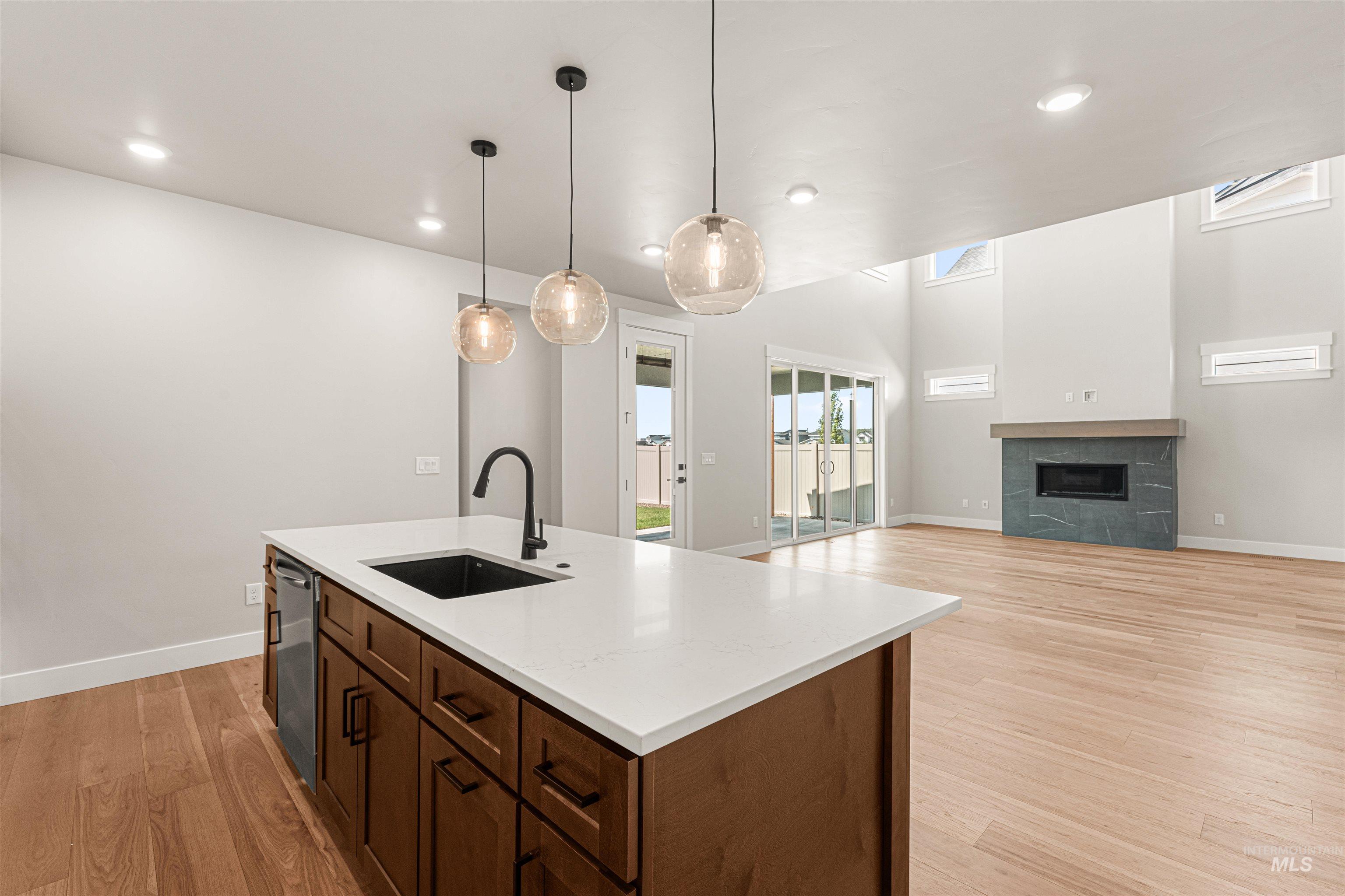 Kitchen featuring light wood-style floors, a tiled fireplace, light countertops, decorative light fixtures, and recessed lighting