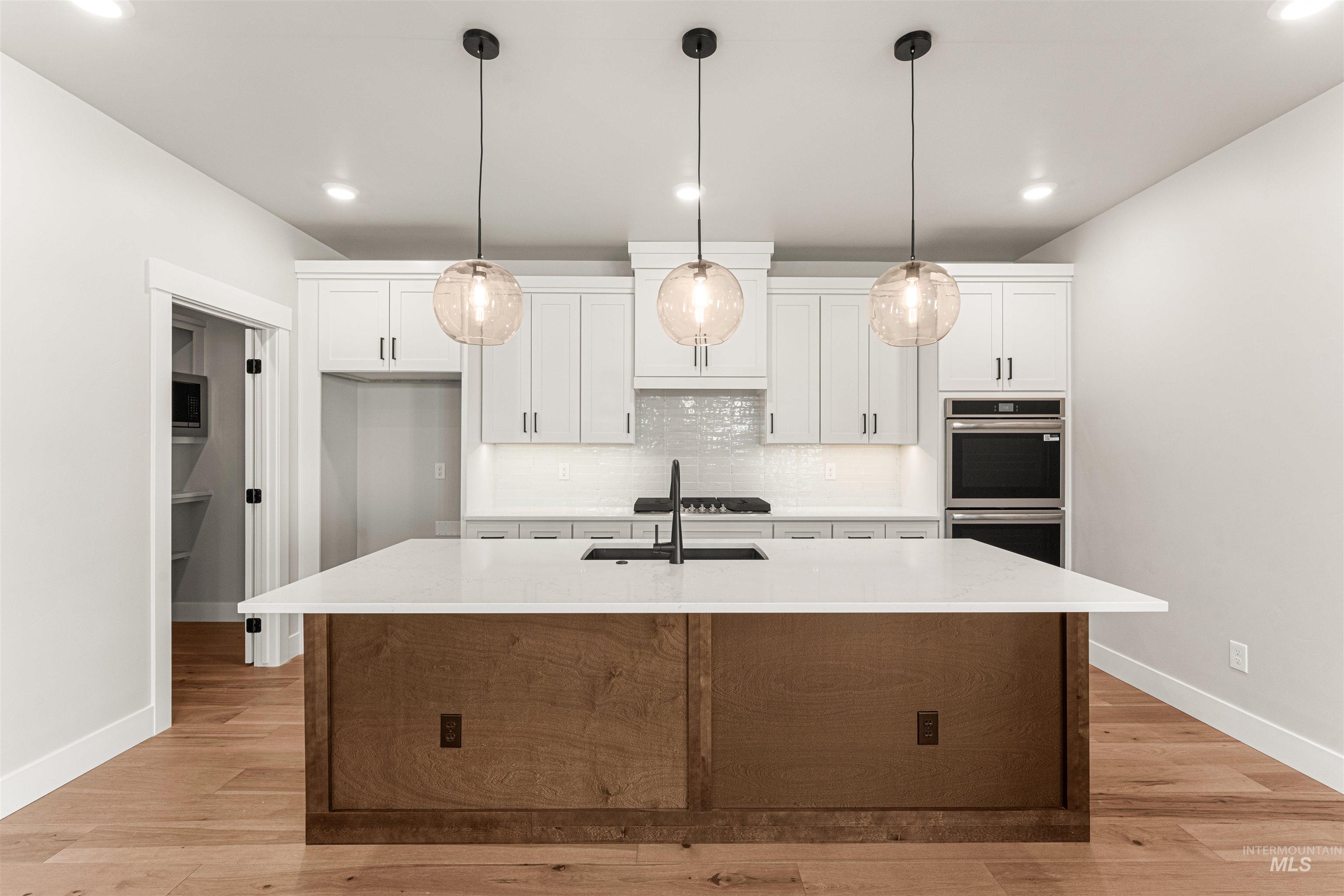 Kitchen with white cabinetry, recessed lighting, double oven, and light countertops