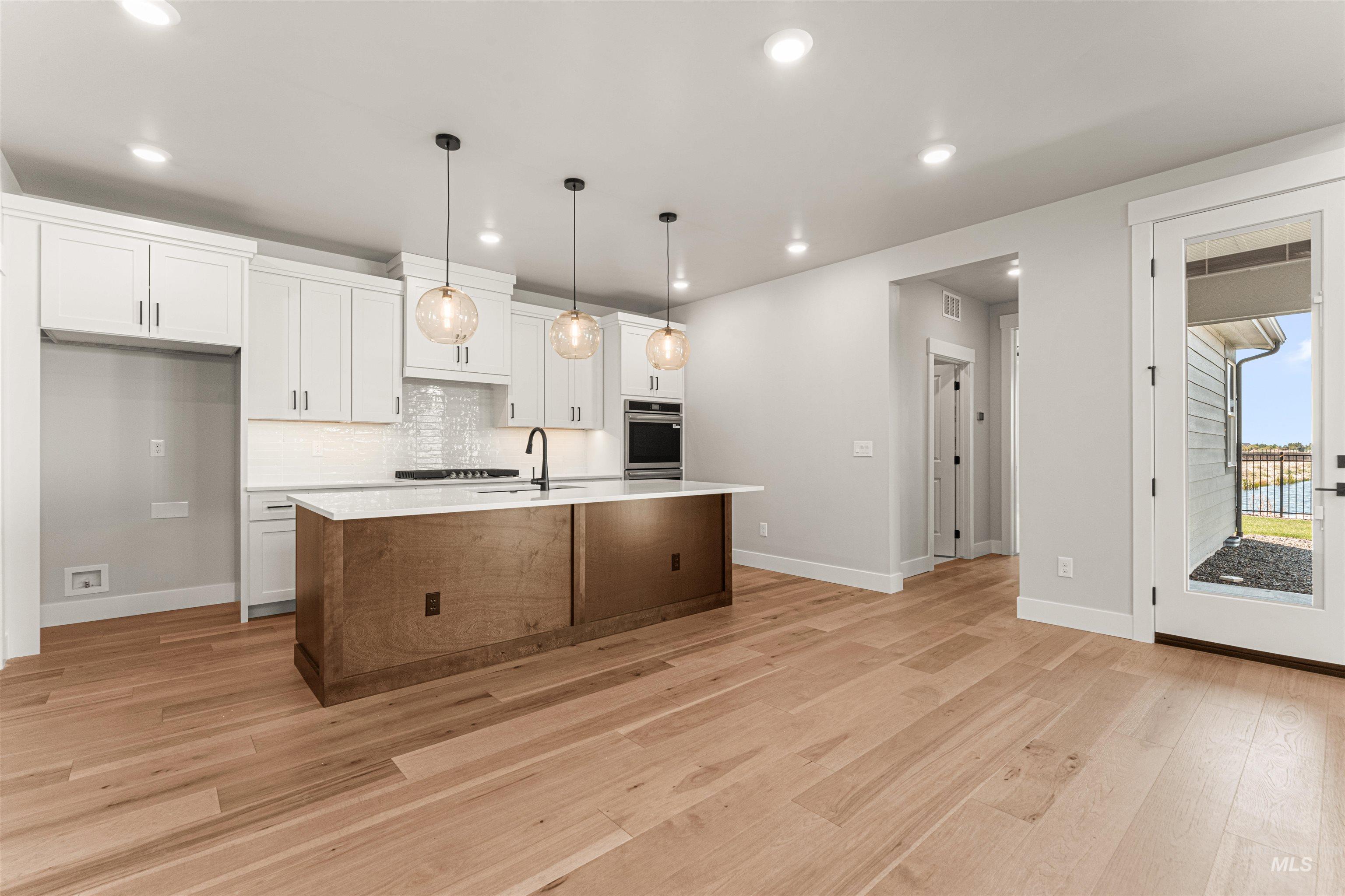 Kitchen with white cabinets, light countertops, light wood-style floors, recessed lighting, and tasteful backsplash