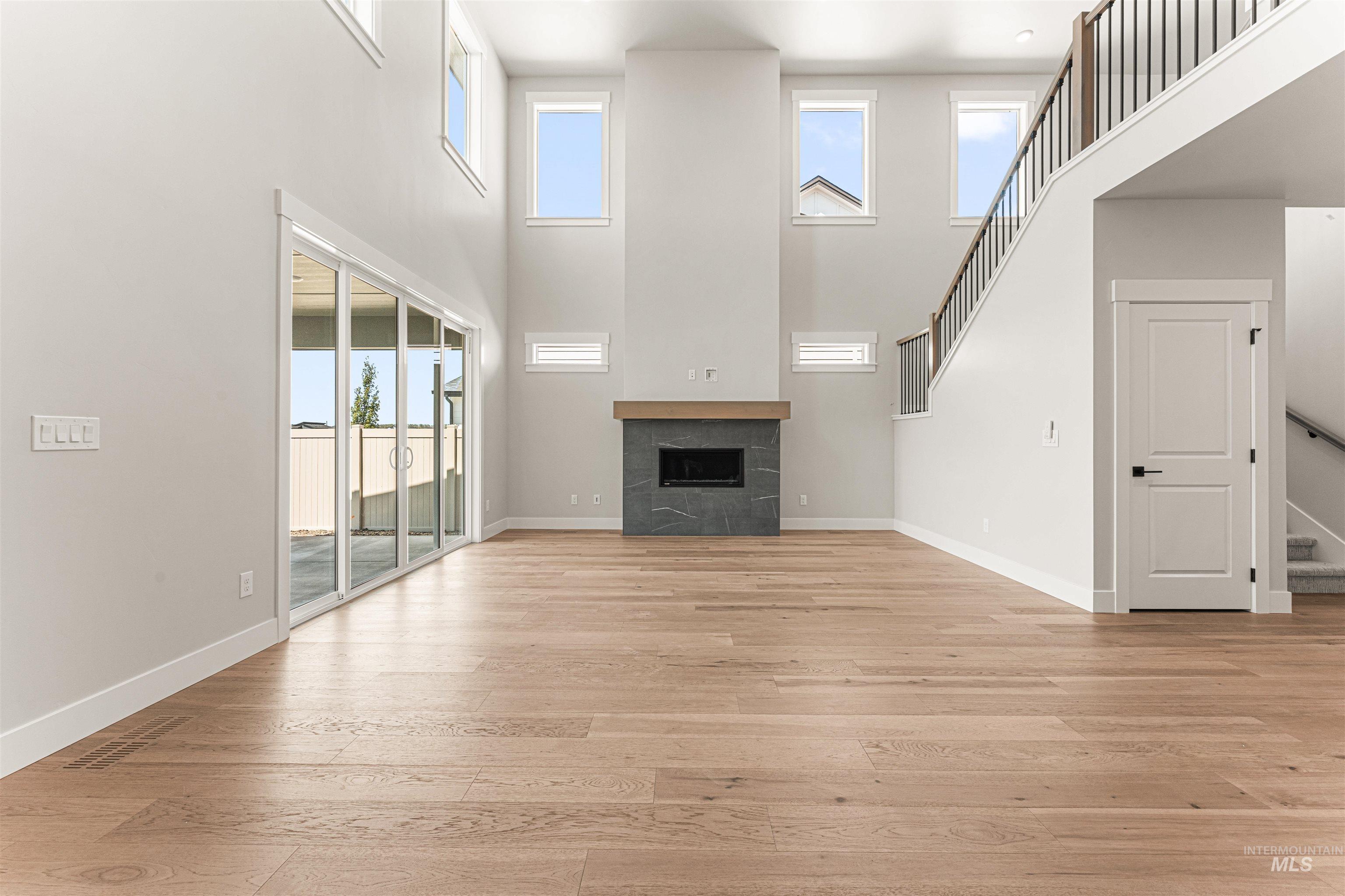 Unfurnished living room featuring light wood-style flooring, a tile fireplace, and healthy amount of natural light