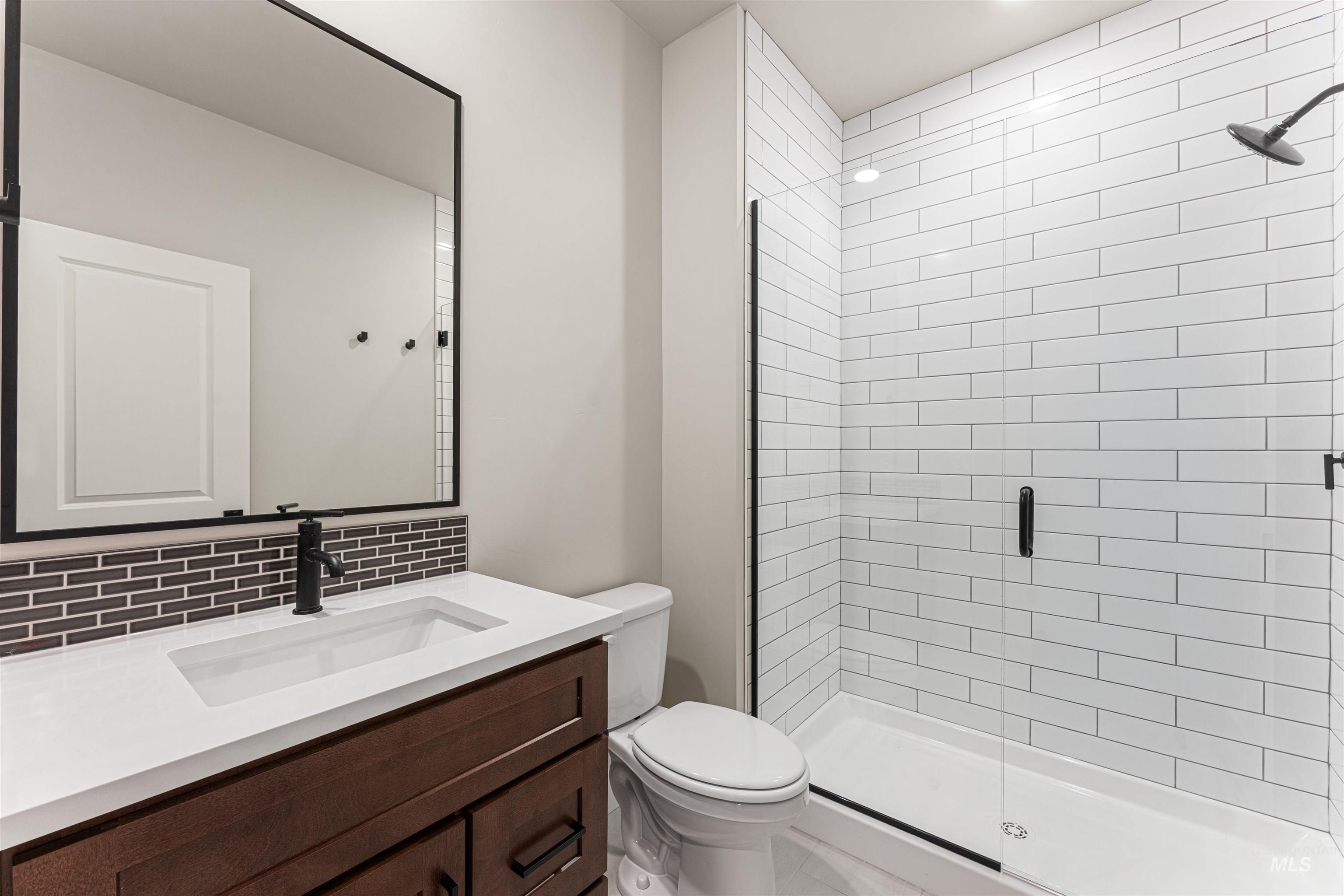 Bathroom featuring a stall shower, vanity, and decorative backsplash