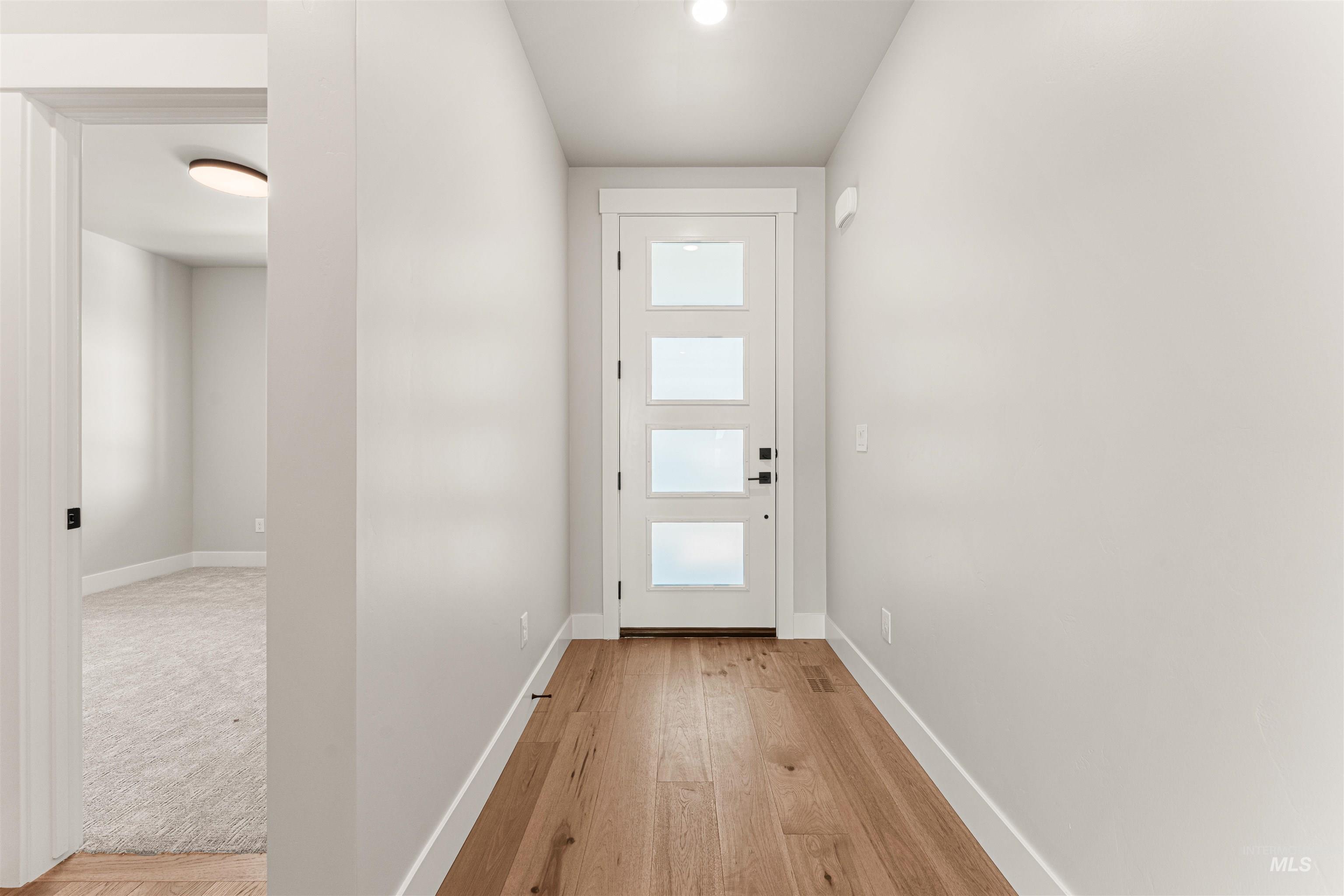 Doorway to outside with light wood-style floors and baseboards