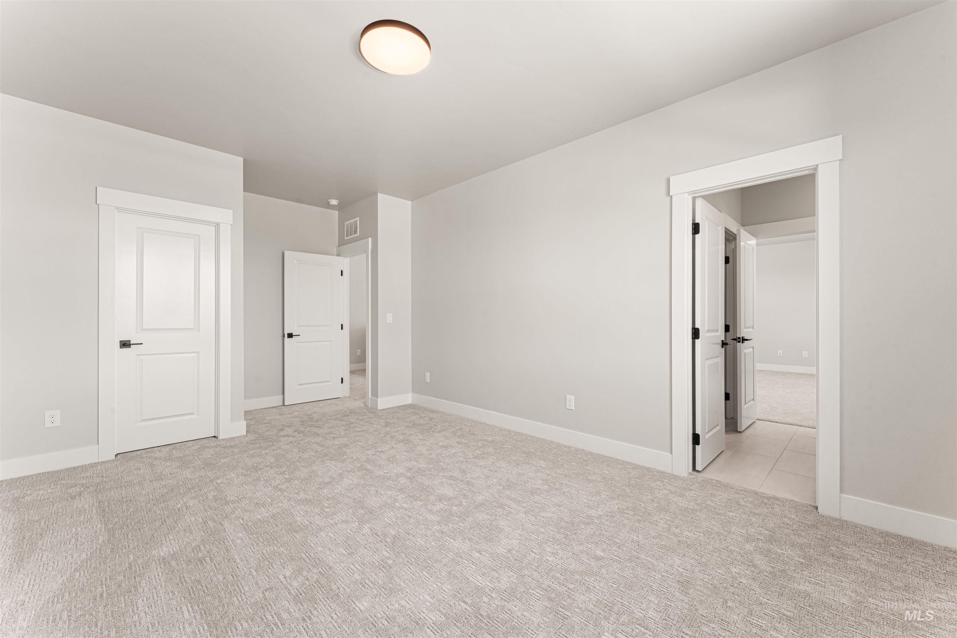 Unfurnished bedroom with light colored carpet and baseboards