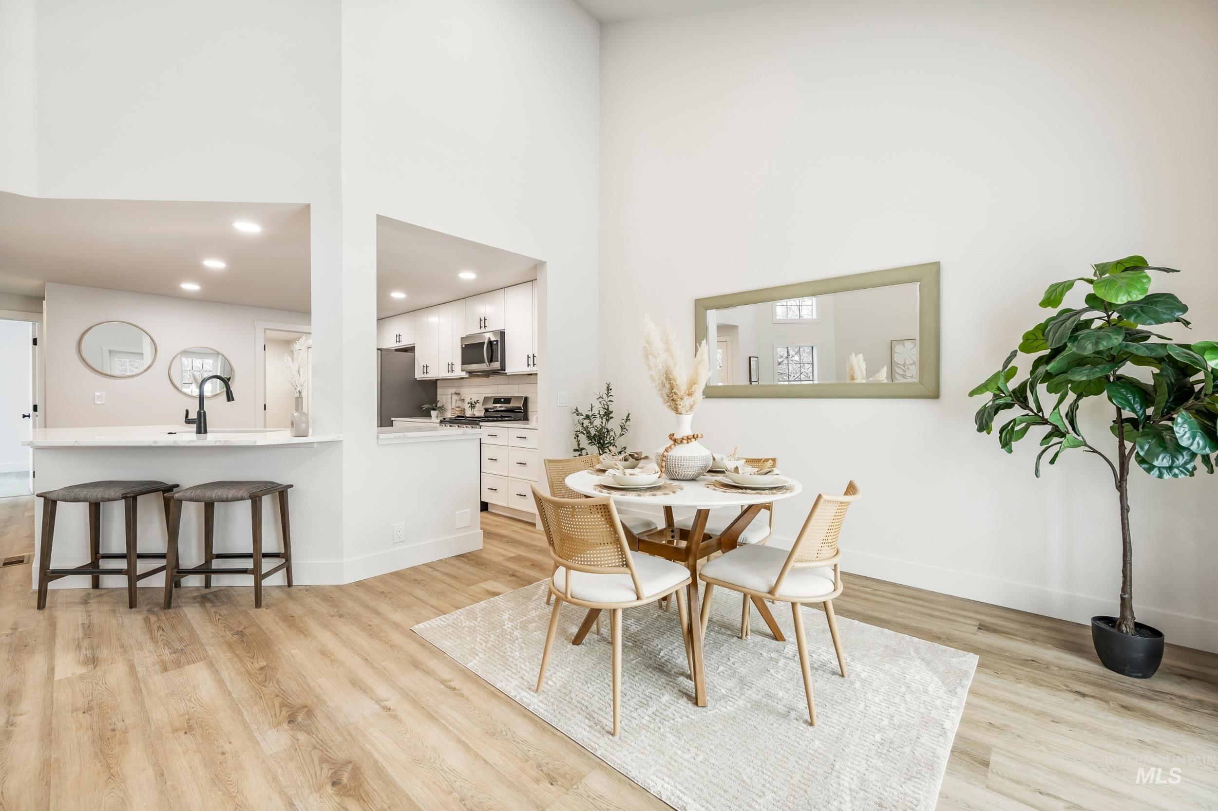 Dining room with a towering ceiling, light wood-style flooring, and recessed lighting