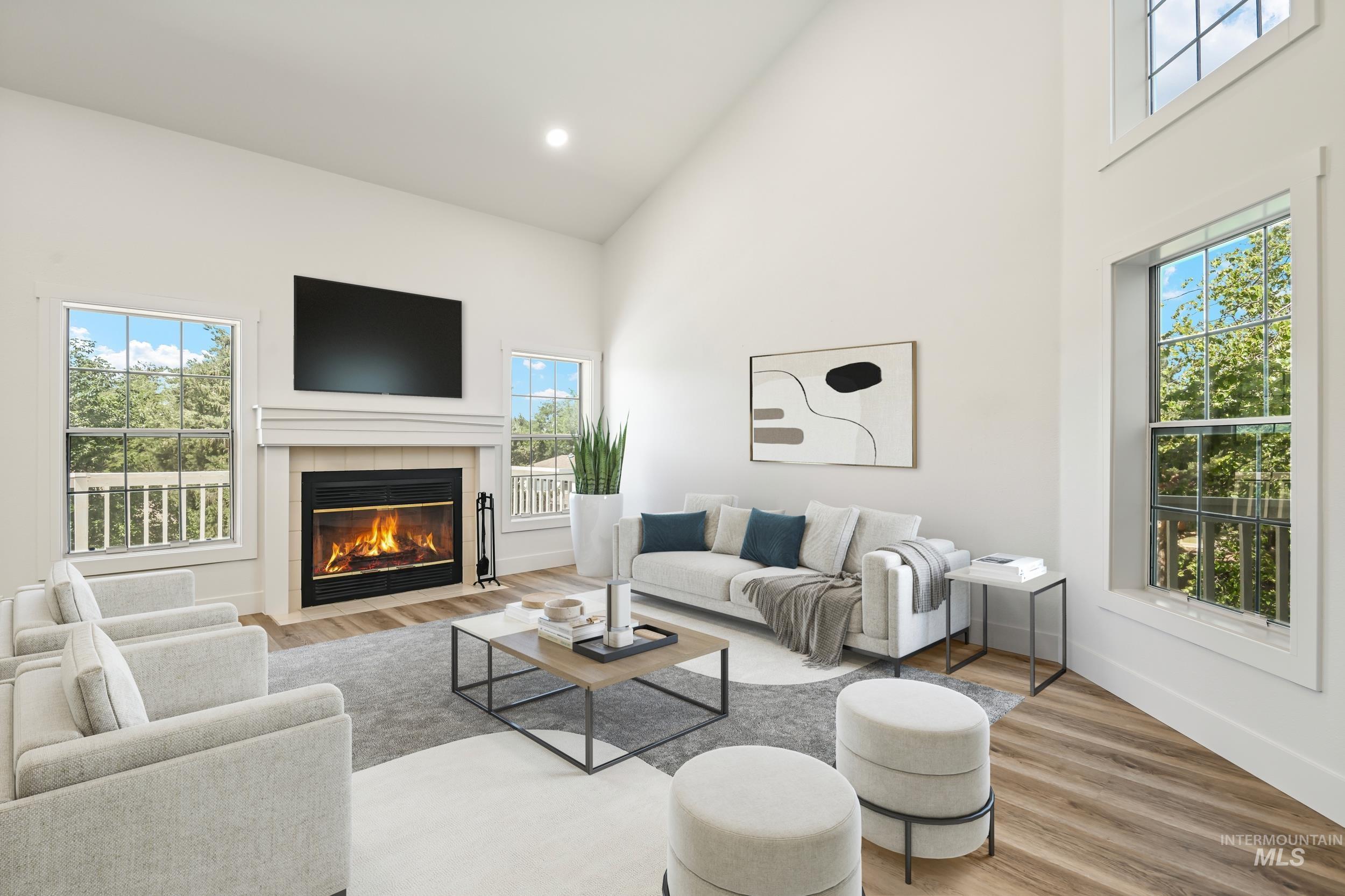 Living area with high vaulted ceiling, wood finished floors, a tile fireplace, and recessed lighting