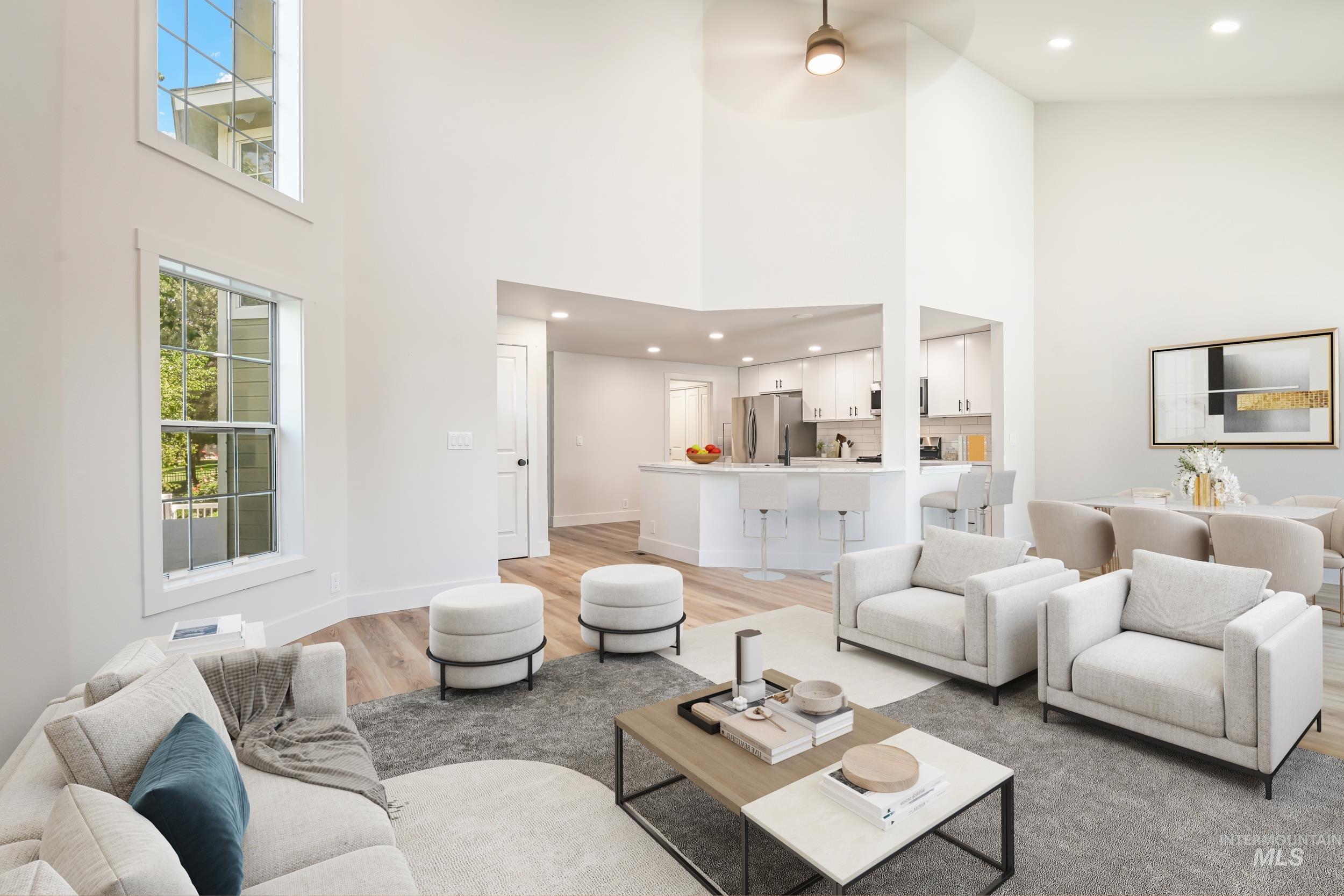 Living area with a high ceiling, light wood finished floors, recessed lighting, and ceiling fan