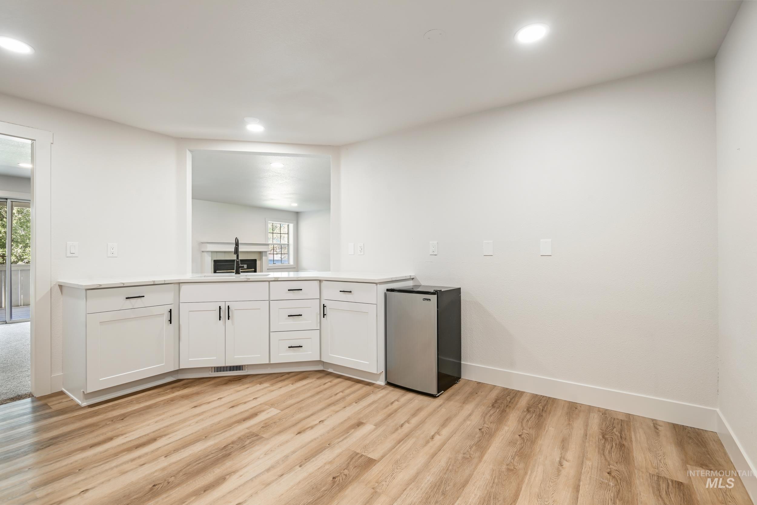 Kitchen with white cabinetry, light countertops, freestanding refrigerator, light wood-type flooring, and recessed lighting