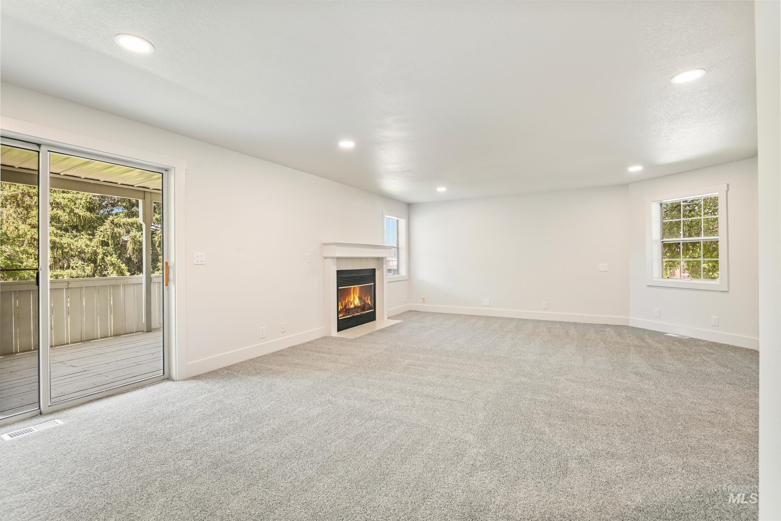 Unfurnished living room with recessed lighting, light carpet, and a fireplace with flush hearth