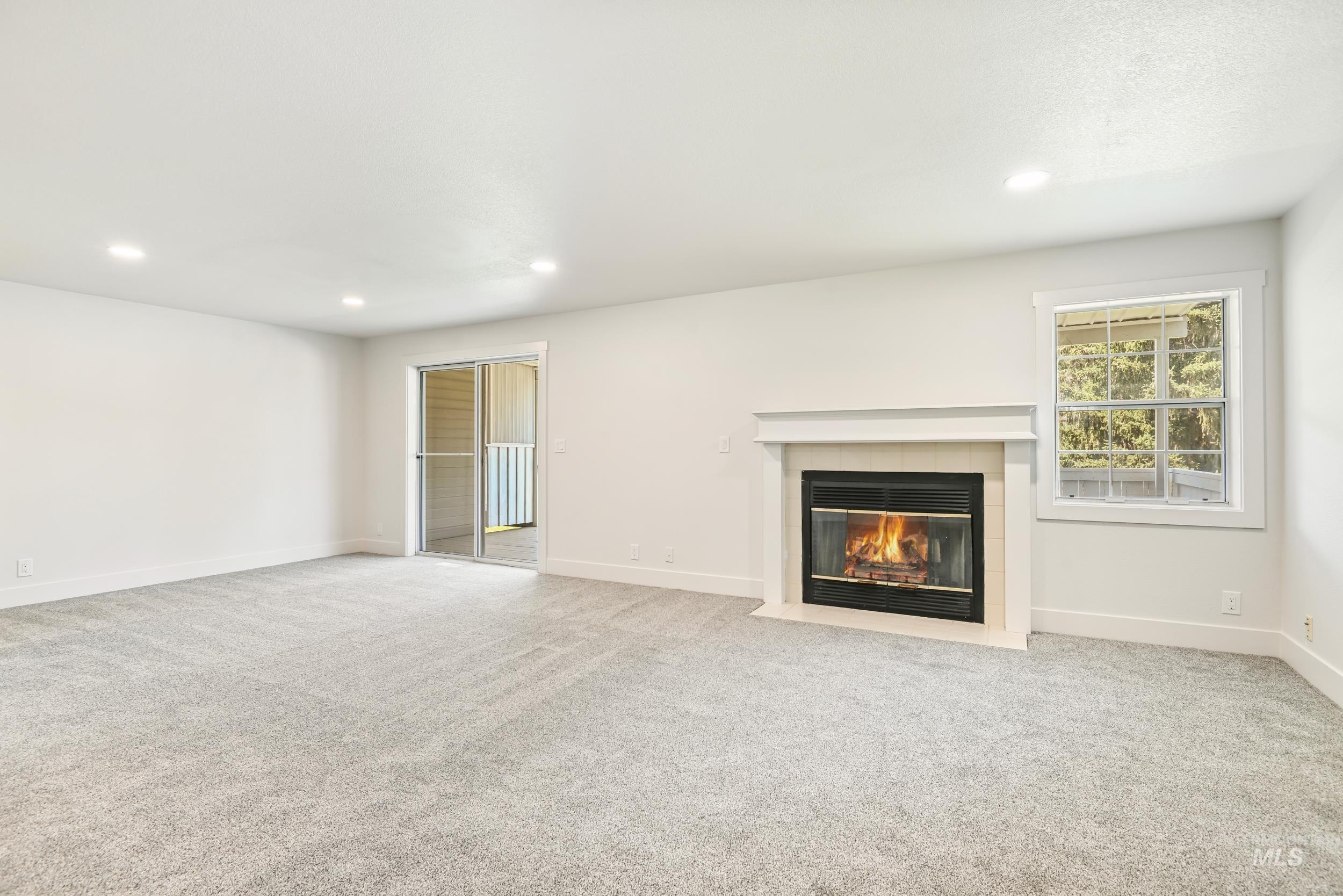 Unfurnished living room with light carpet, recessed lighting, and a tiled fireplace