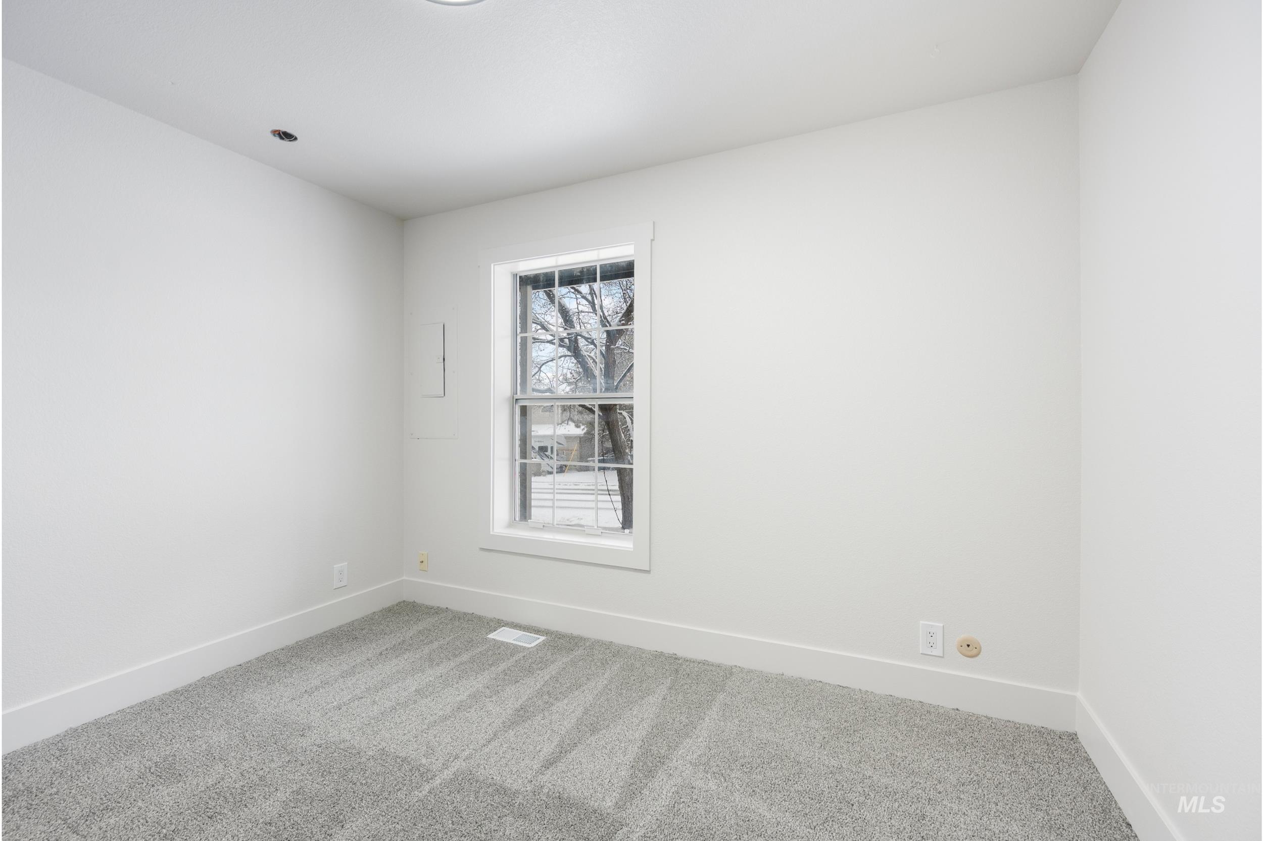Carpeted spare room featuring baseboards