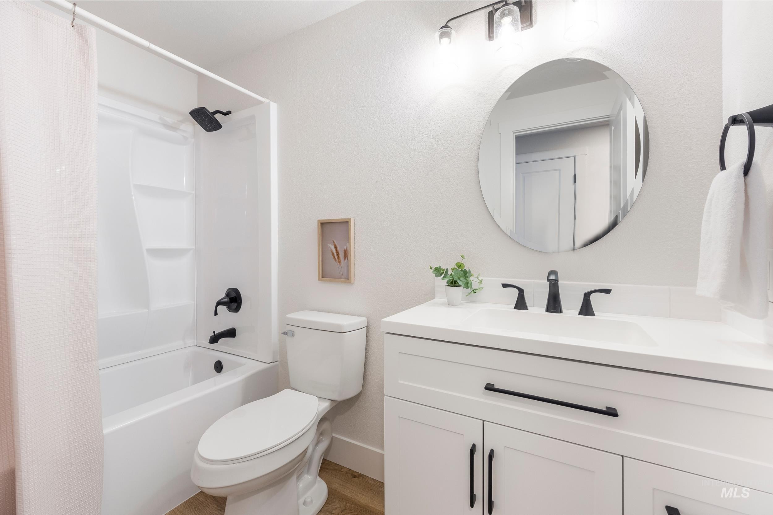 Full bath featuring shower / tub combo, vanity, and a textured wall