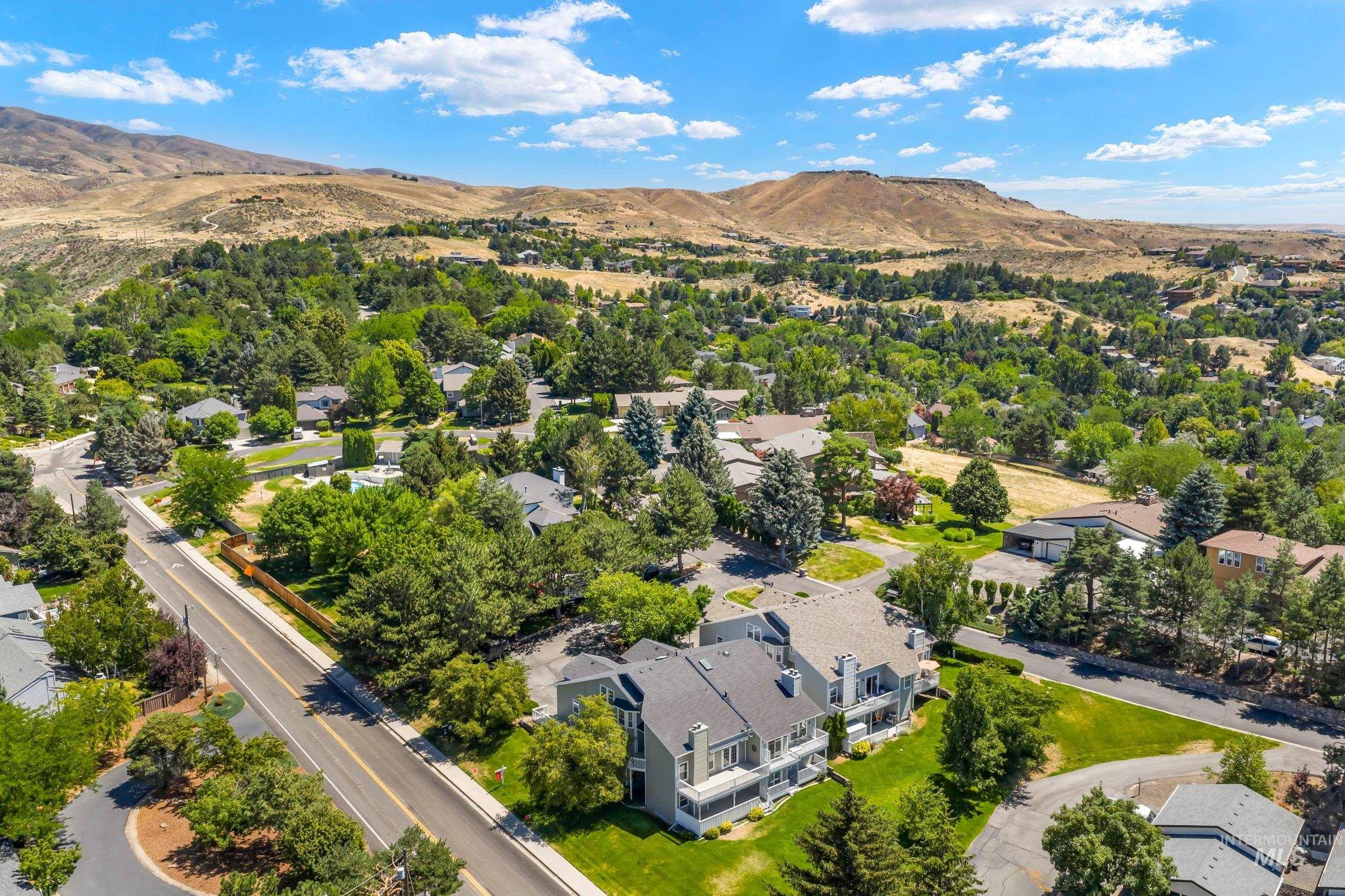 Aerial perspective of suburban area with a mountainous background and a tree filled landscape