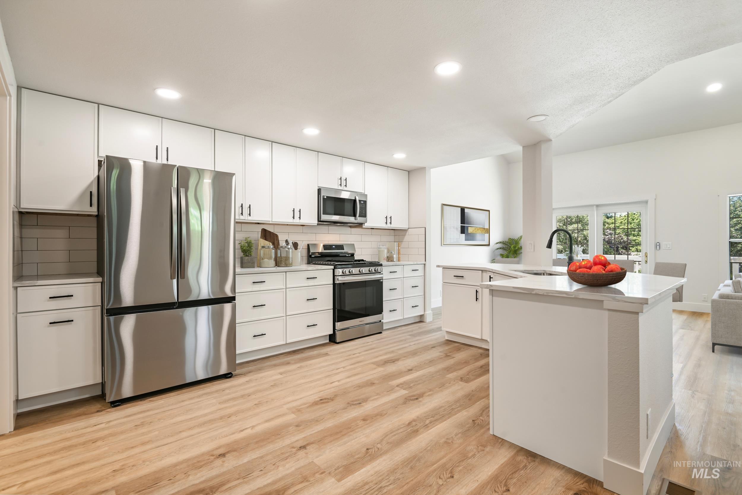 Kitchen featuring appliances with stainless steel finishes, recessed lighting, white cabinets, backsplash, and light wood-type flooring