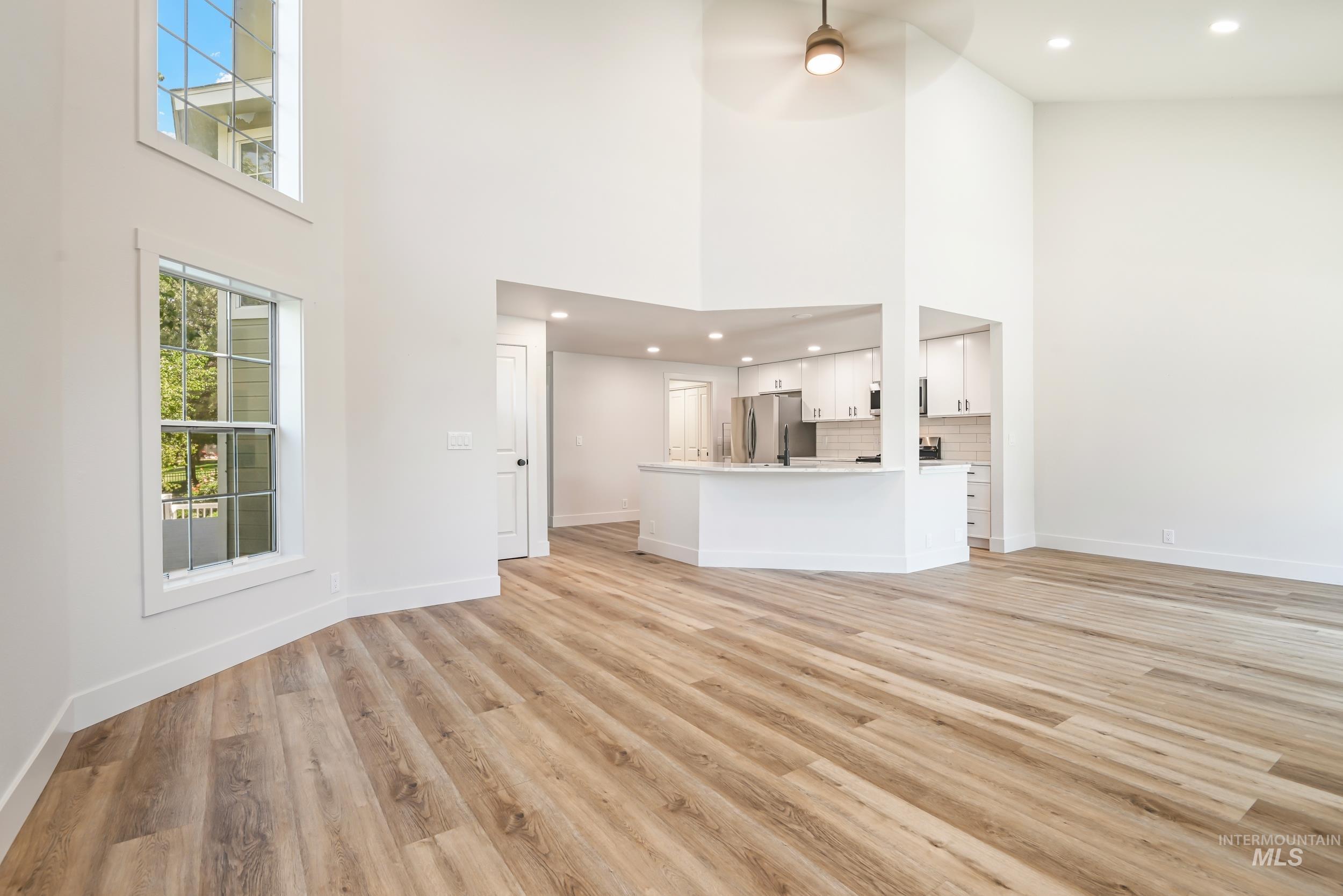 Unfurnished living room with a high ceiling, light wood-type flooring, recessed lighting, and a ceiling fan