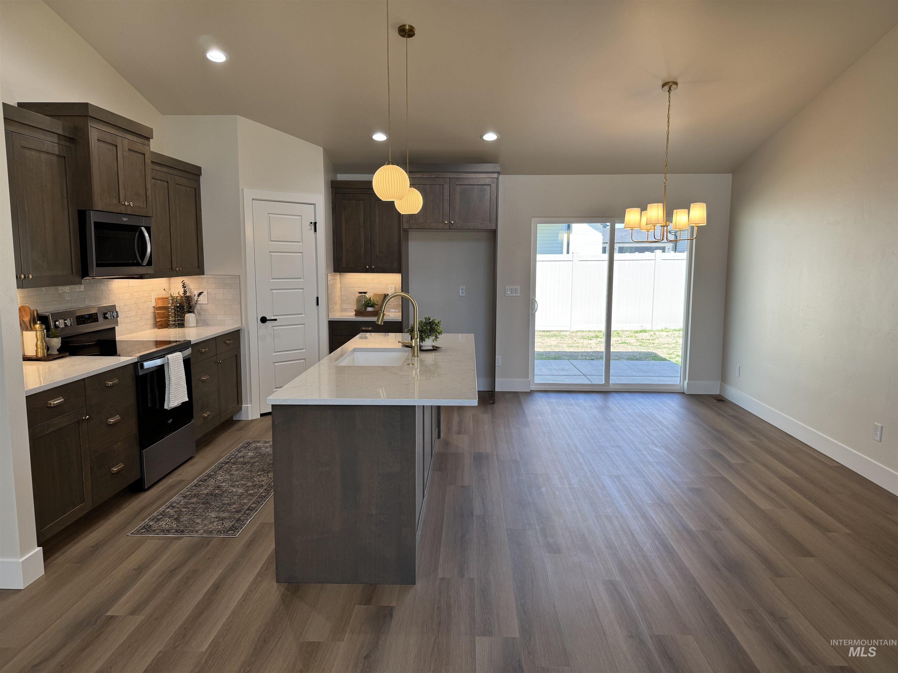 Kitchen featuring stainless steel appliances, a chandelier, backsplash, dark wood finished floors, and dark brown cabinetry
