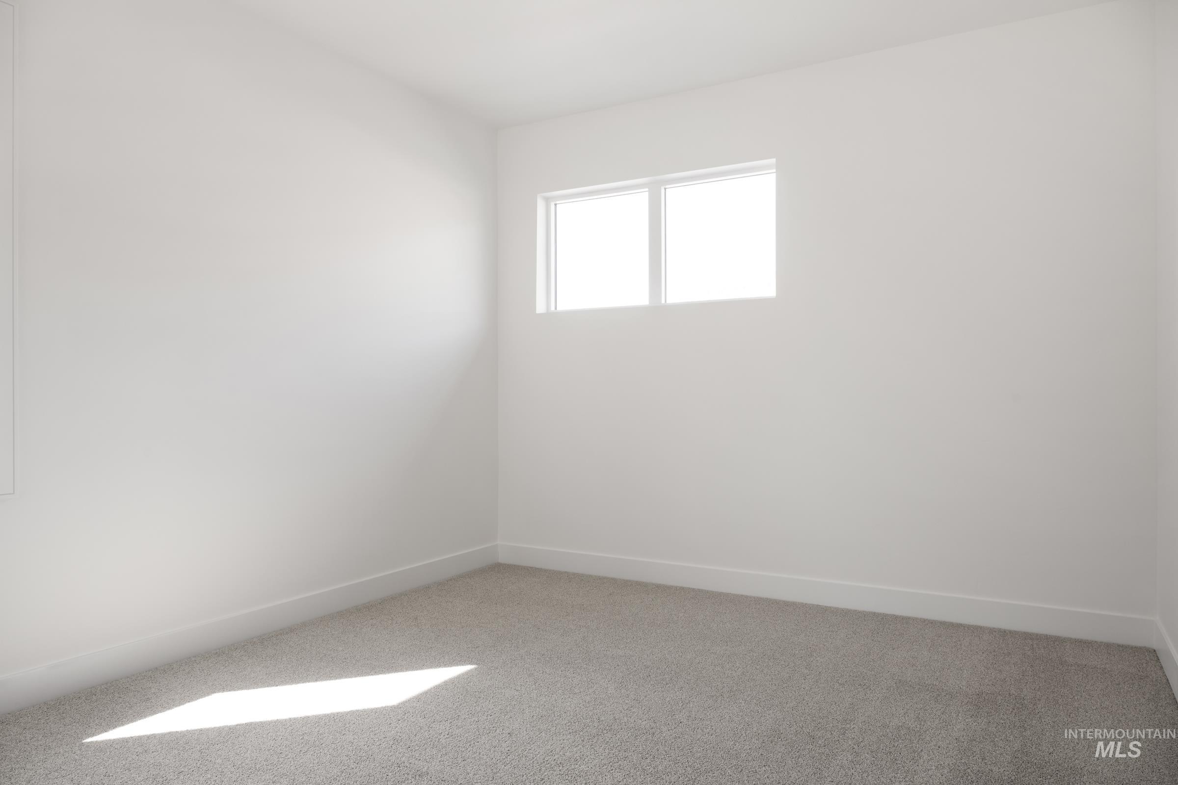 Empty room featuring light colored carpet and baseboards