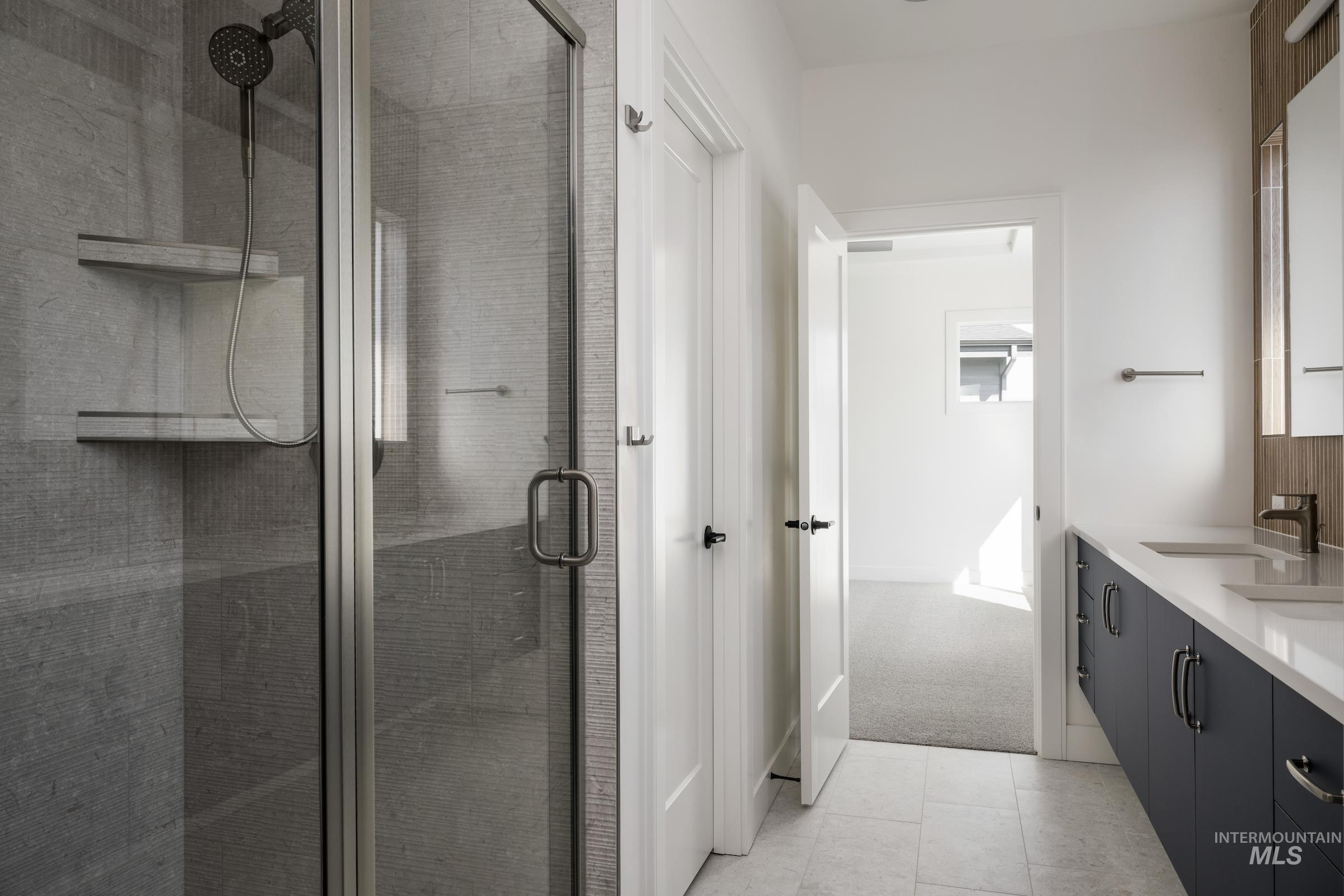 Full bathroom featuring double vanity, a shower stall, and tile patterned flooring