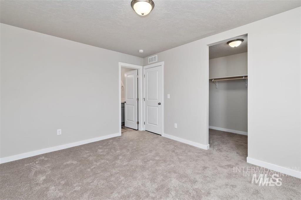 Unfurnished bedroom featuring carpet floors, a spacious closet, and a textured ceiling