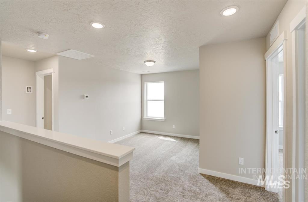 Spare room with light colored carpet, a smoke detector, and a textured ceiling