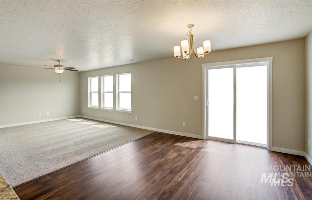 Unfurnished room featuring a chandelier, a textured ceiling, dark wood finished floors, and ceiling fan
