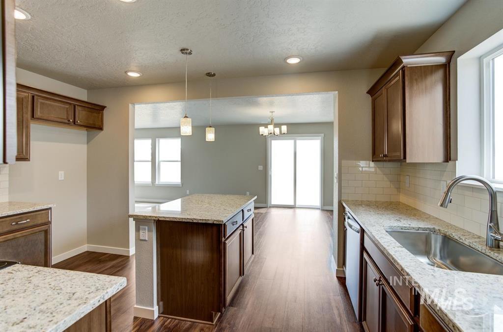 Kitchen featuring dishwasher, backsplash, a textured ceiling, dark wood-style floors, and decorative light fixtures