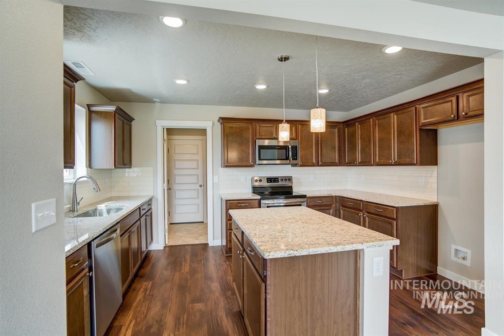 Kitchen featuring stainless steel appliances, a kitchen island, dark wood-style flooring, tasteful backsplash, and recessed lighting