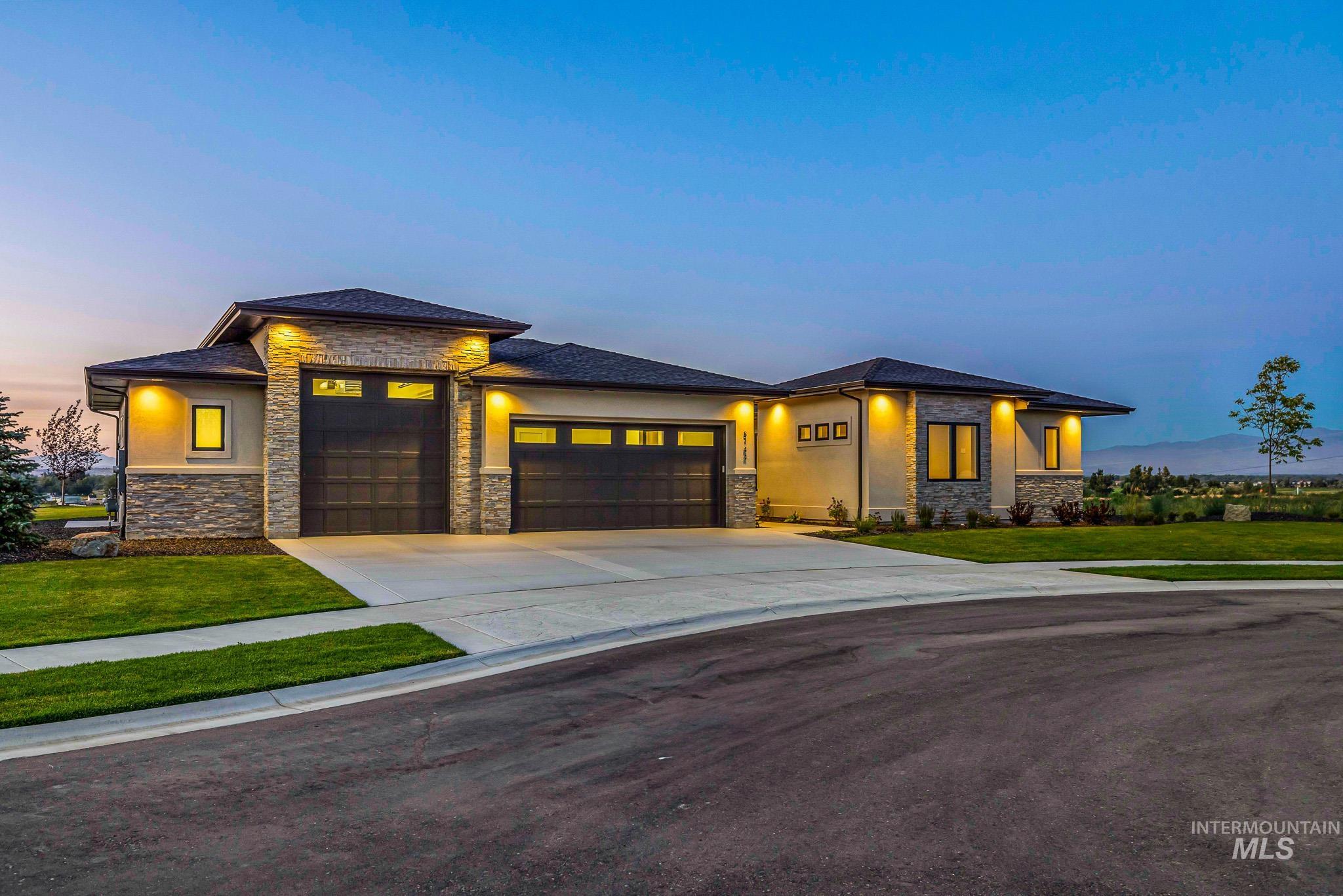 Prairie-style home featuring an attached garage, stone siding, concrete driveway, and a yard