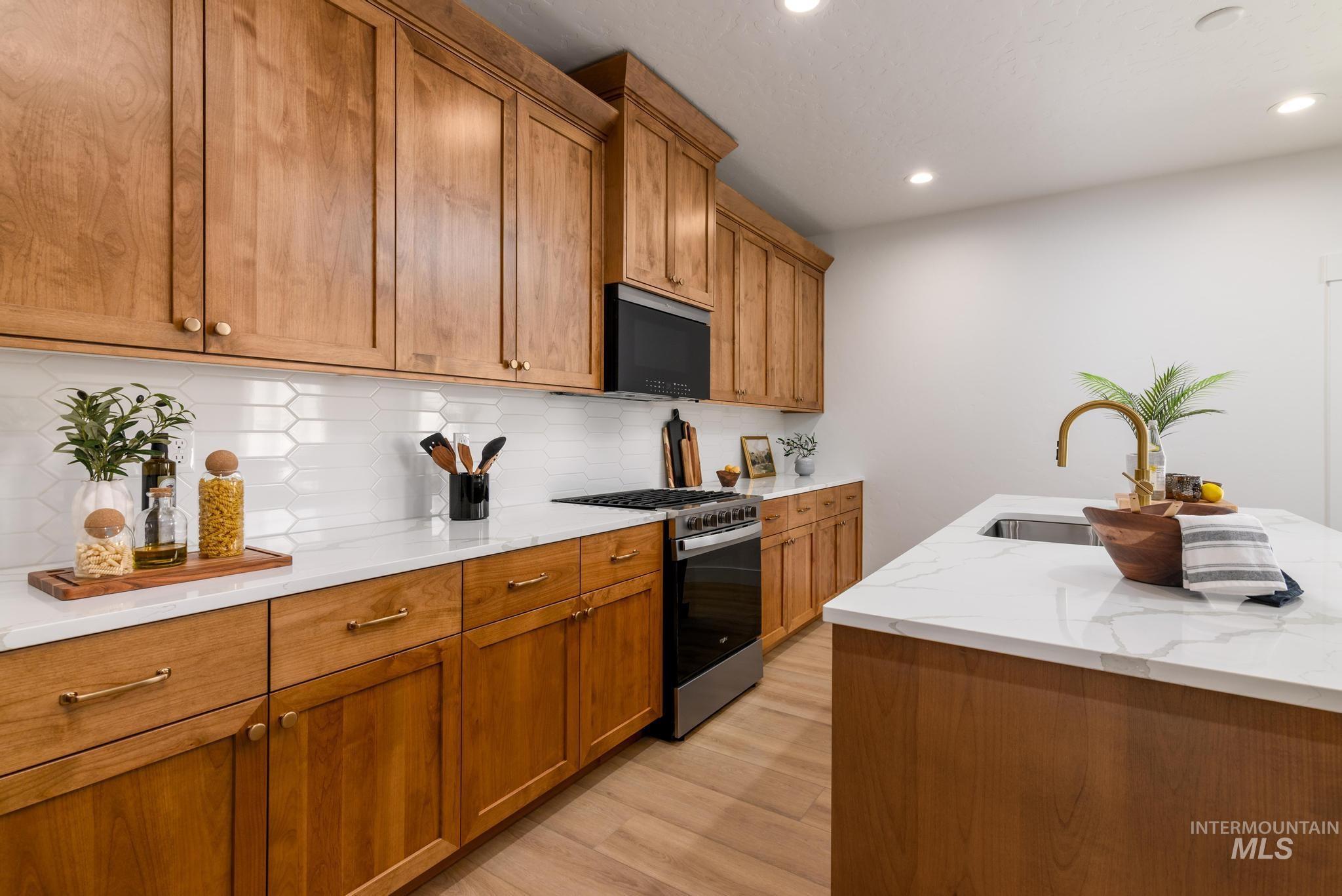 Kitchen featuring gas range, light wood-style floors, brown cabinetry, recessed lighting, and decorative backsplash