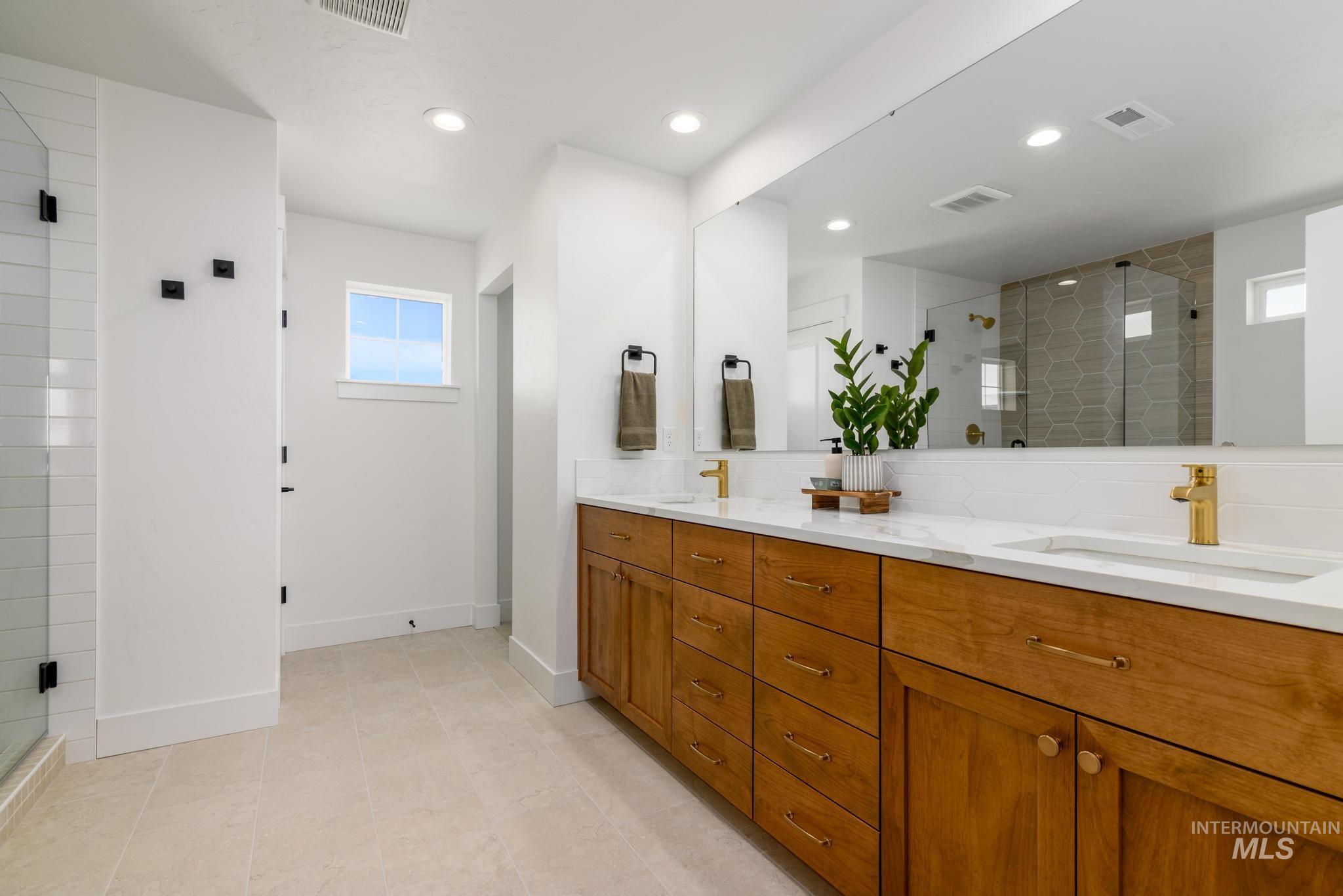 Full bathroom with double vanity, a stall shower, and recessed lighting